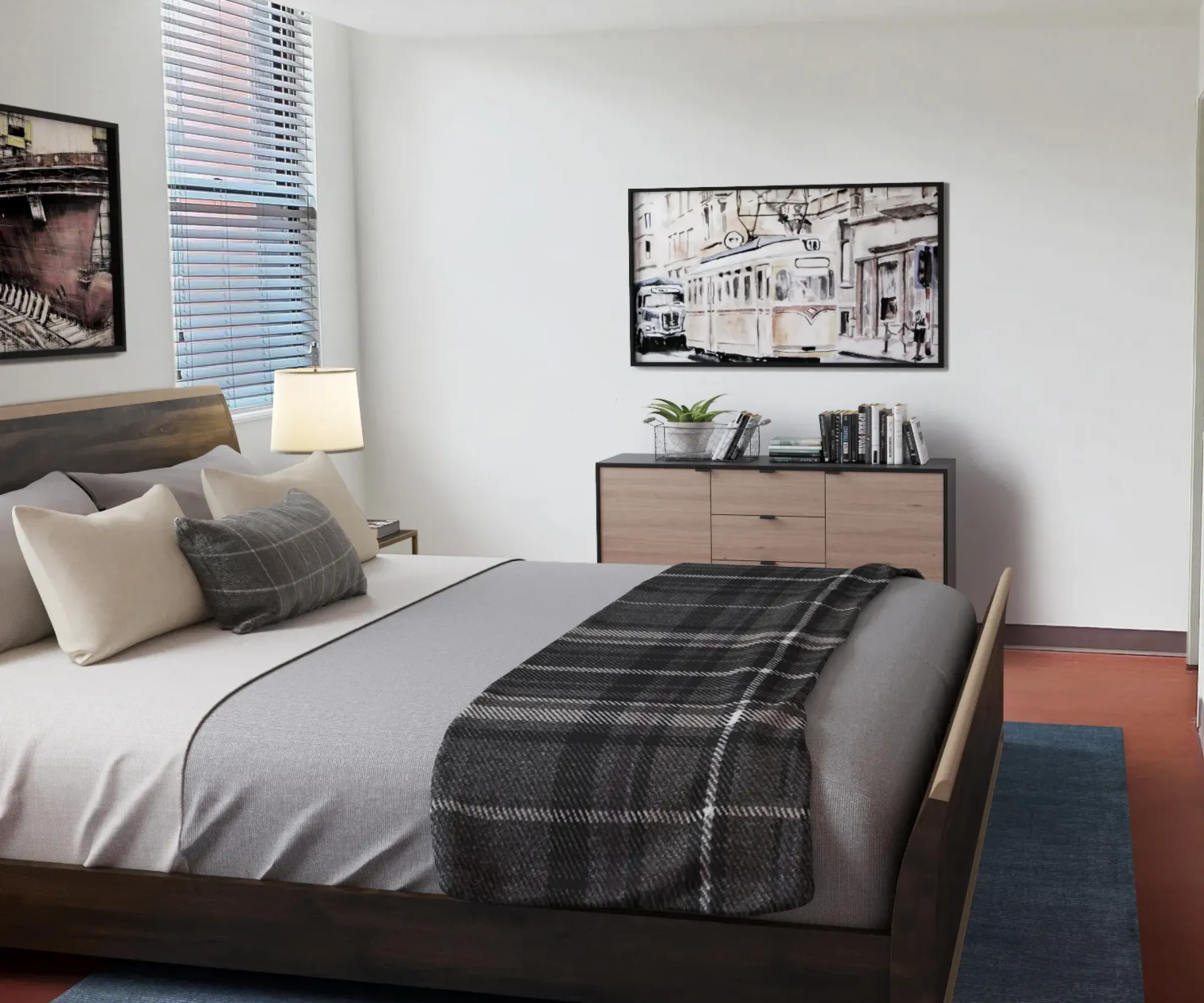 Aeon Affordable Homes and Community Minimalist bedroom in affordable apartment homes with a wooden bed, gray bedding, plaid blanket, dresser, framed artwork, and a blue rug.