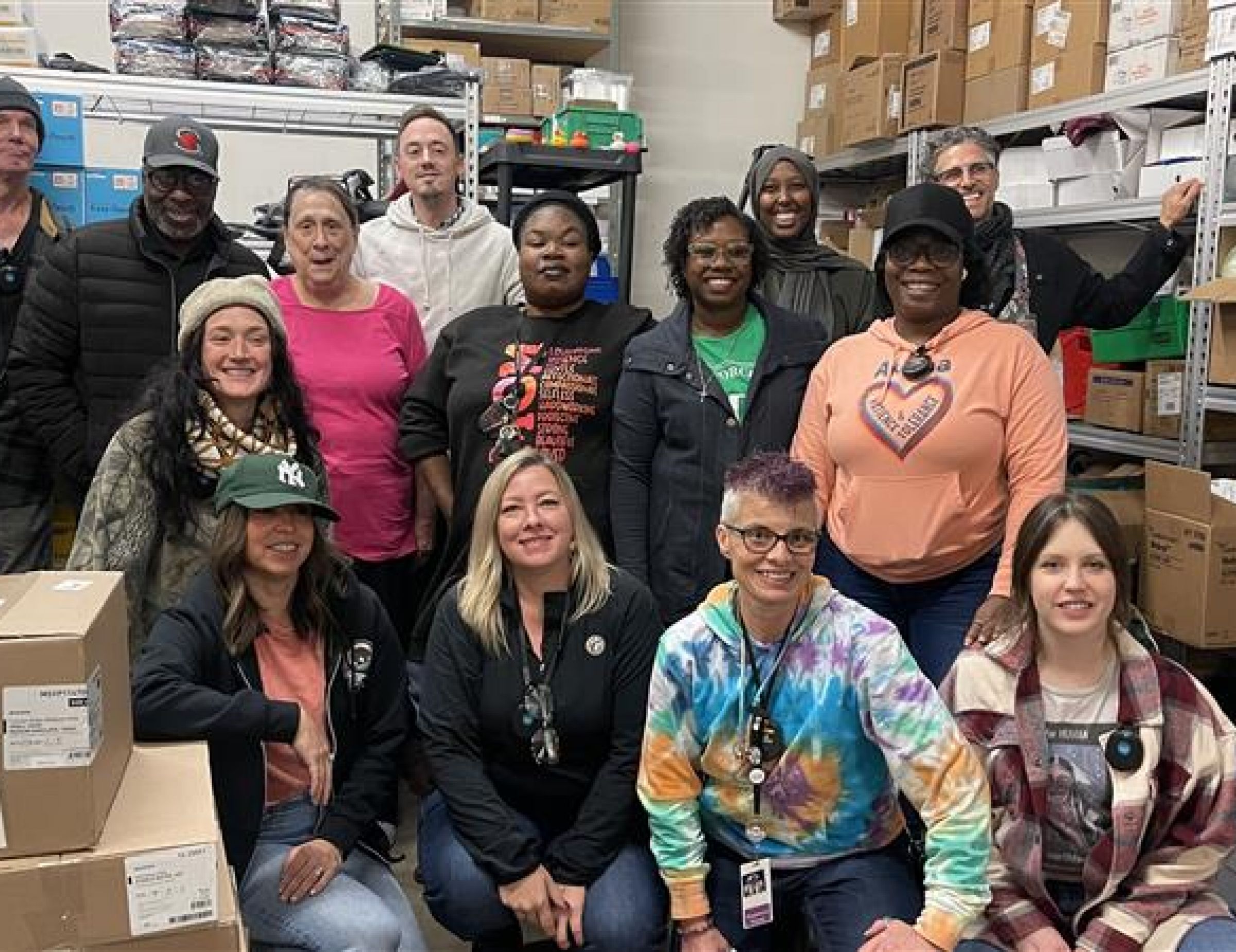 Aeon Affordable Homes A group of people smiling and posing together in a storage room with shelves and boxes in the background.
