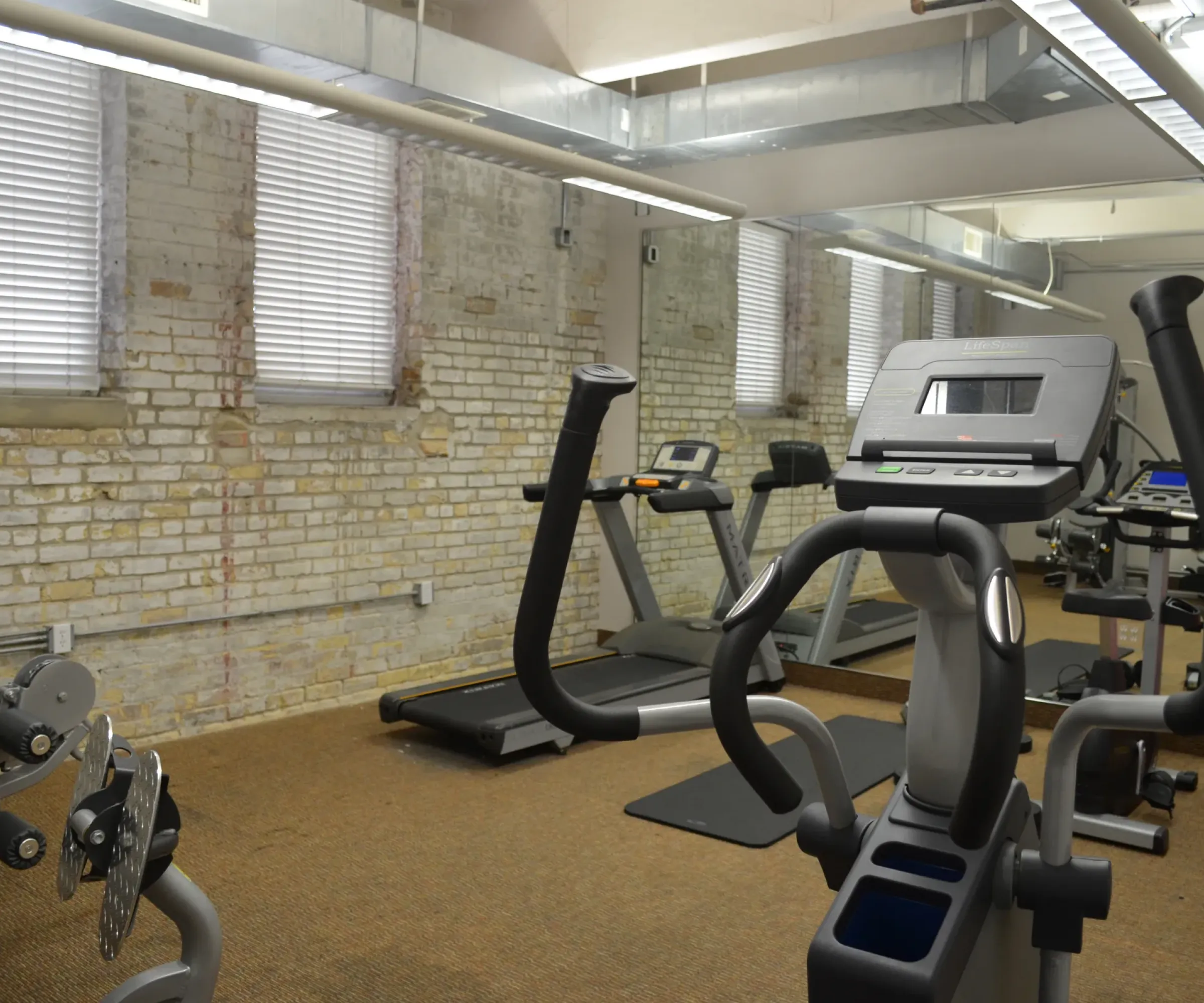 Aeon Affordable Homes and Community A gym with treadmills, exercise bikes, and exposed brick walls, ideal for those living in affordable apartment homes.