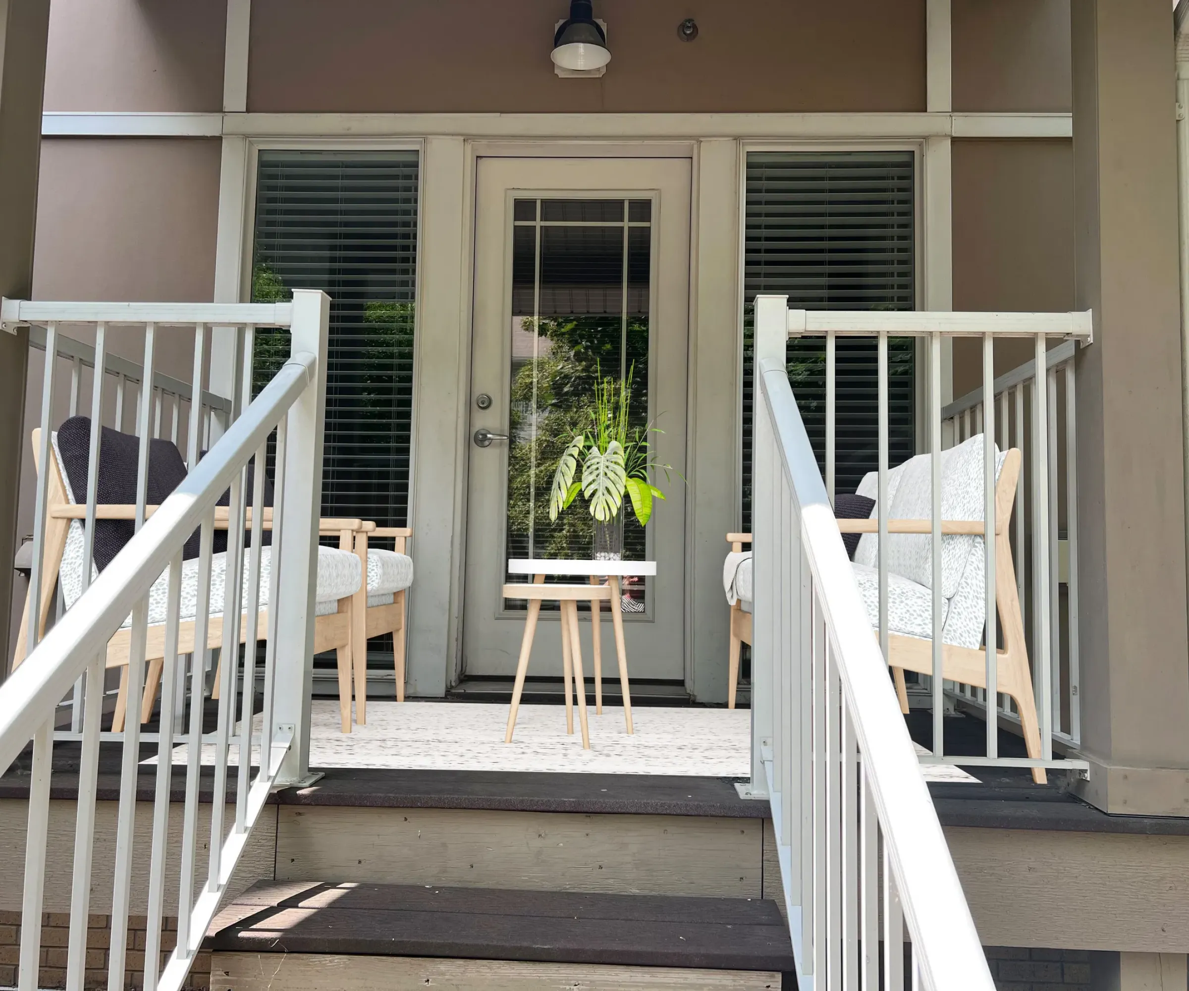 Aeon Affordable Homes and Community Cozy porch at our affordable apartment homes, with two chairs, a table, a plant, and steps leading up to it.