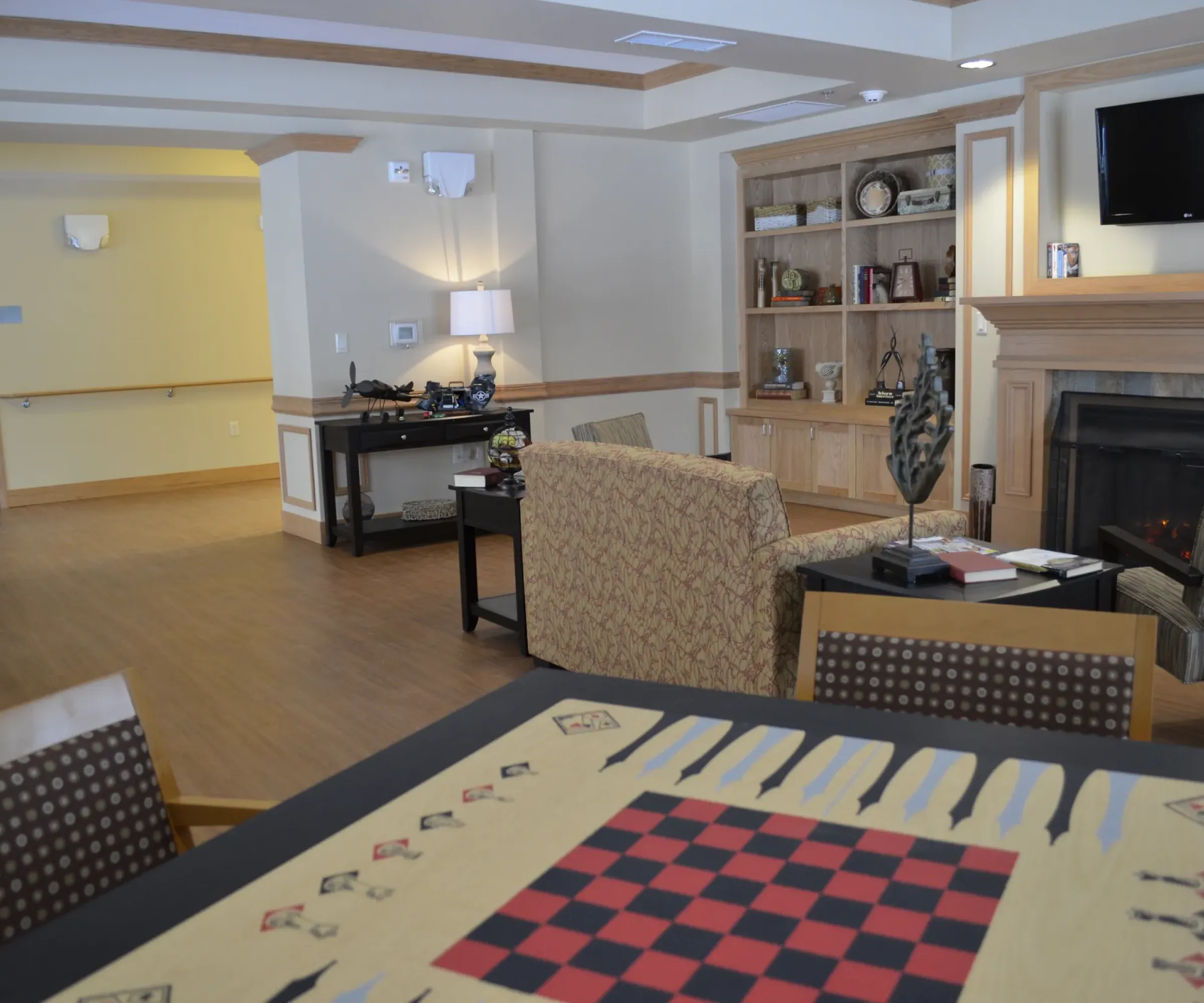 Aeon Affordable Homes and Community An affordable apartment home featuring a cozy living room with a fireplace, bookshelves, a TV, and a chess/checkers board design table.