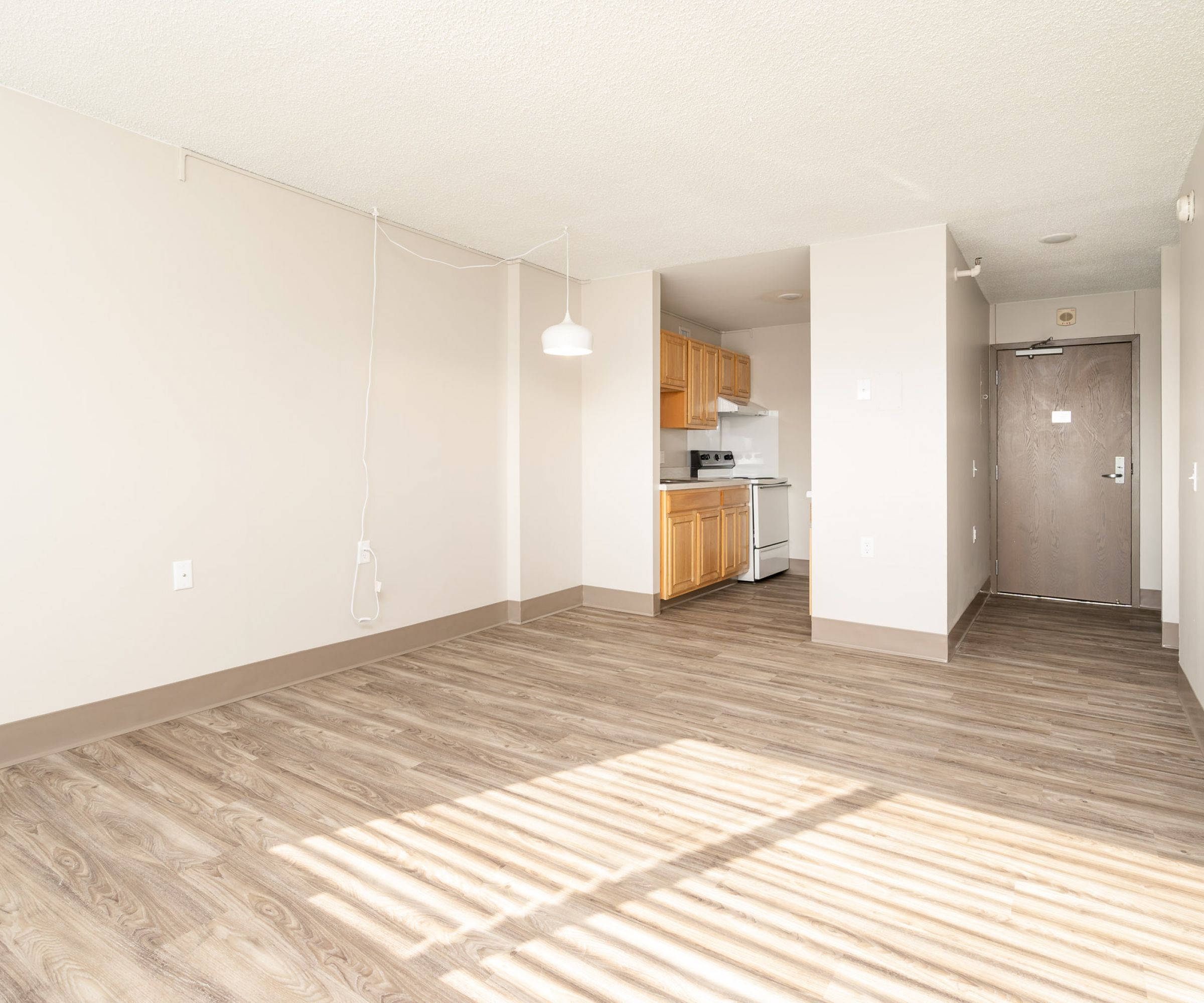 Aeon Affordable Homes and Community Affordable apartment homes with wooden floors, a pendant light, a cozy kitchen area, and sunlight streaming through window blinds.