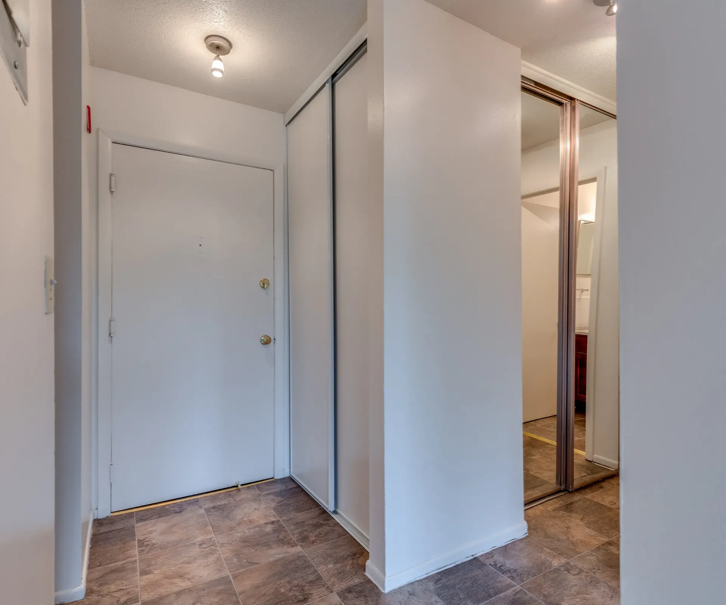 Aeon Affordable Homes and Community Narrow hallway with white walls, a closed door, and a sliding closet in affordable apartment homes.