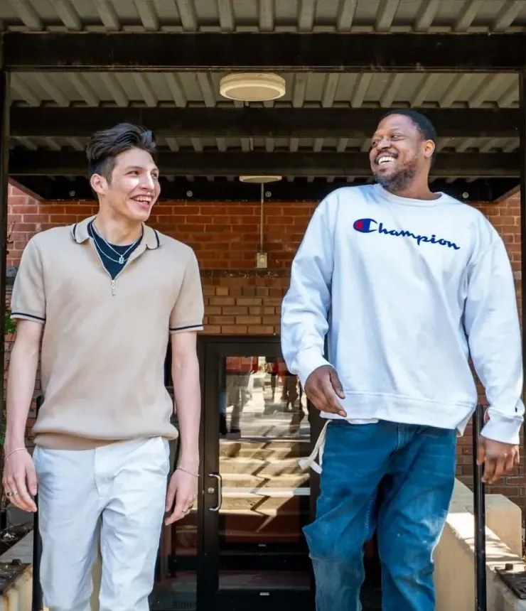 Aeon Affordable Homes with two young men walking out of an apartment entrance and smiling