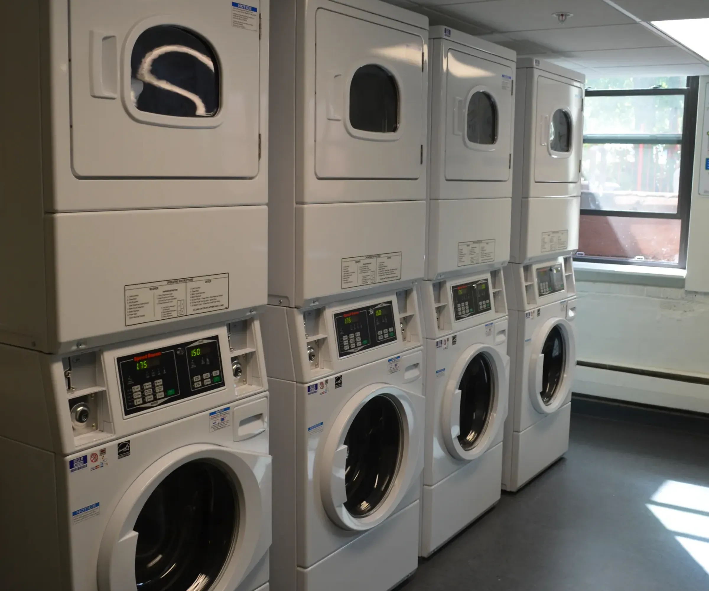 Aeon Affordable Homes and Community A row of stacked washers and dryers in an affordable apartment home's laundry room with a window.