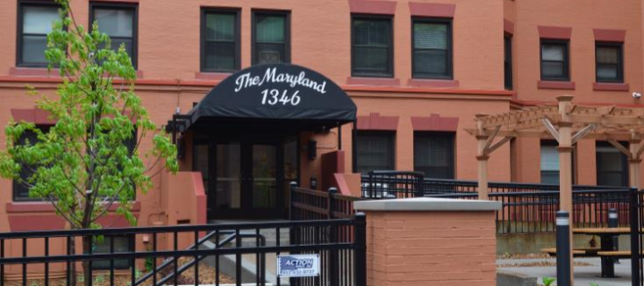 Aeon Affordable Homes and Community Entrance of a brick building with "The Maryland 1346" on a black awning, surrounded by a black fence. Aeon Affordable Homes and Community A brick apartment building with a black canopy displaying "The Maryland 1346" above the entrance. The Maryland entrance The Maryland entrance