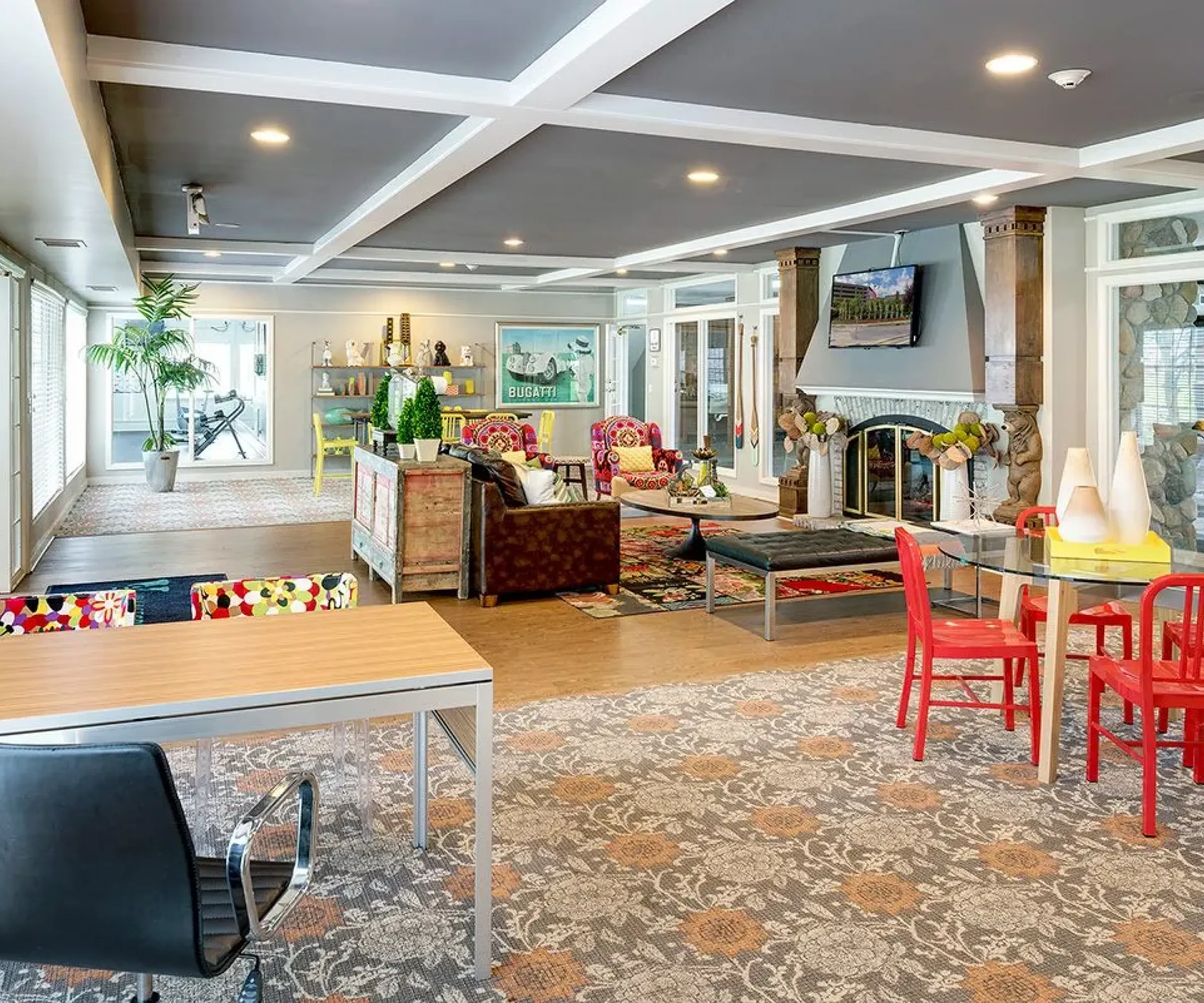 Aeon Affordable Homes Spacious room with colorful decor, tables, chairs, fireplace, and large windows letting in natural light at Blooming Meadows South.