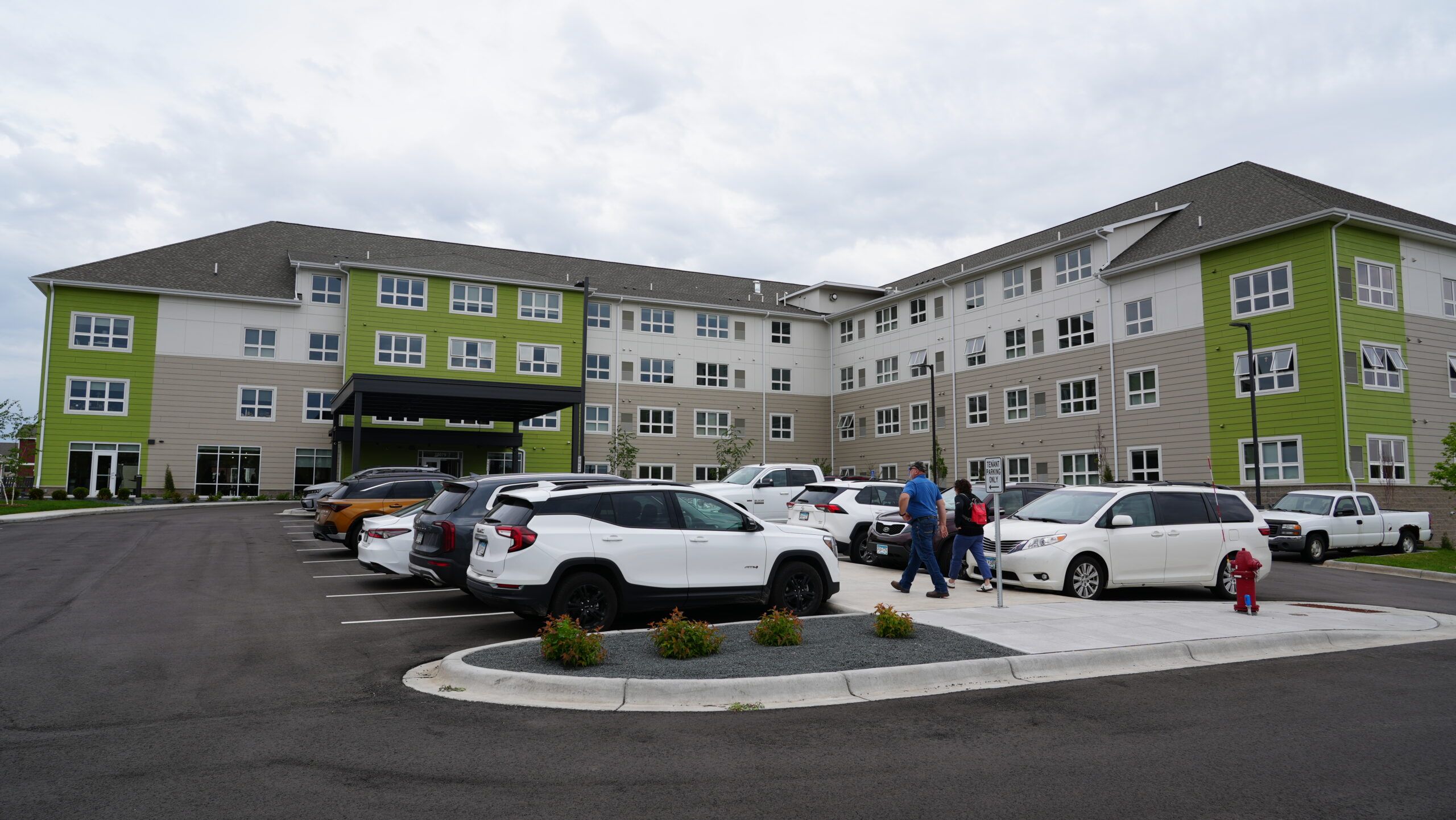 Aeon Affordable Homes A red-brick apartment building stands beside a modern glass skyscraper reflecting the city skyline.
