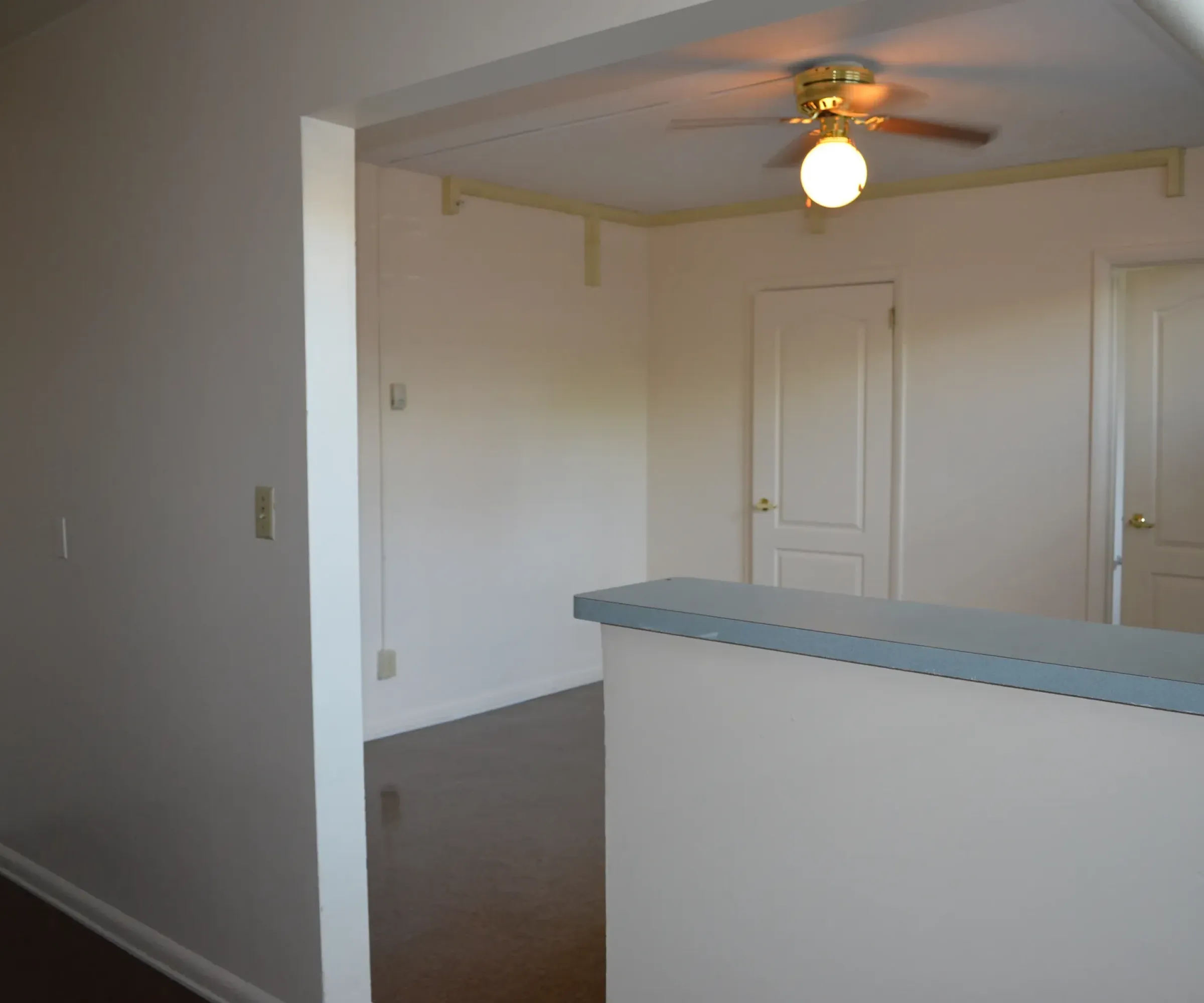 Aeon Affordable Homes and Community Affordable apartment homes with light beige walls, a ceiling fan, closed doors, and a partial divider viewed from an adjacent space.
