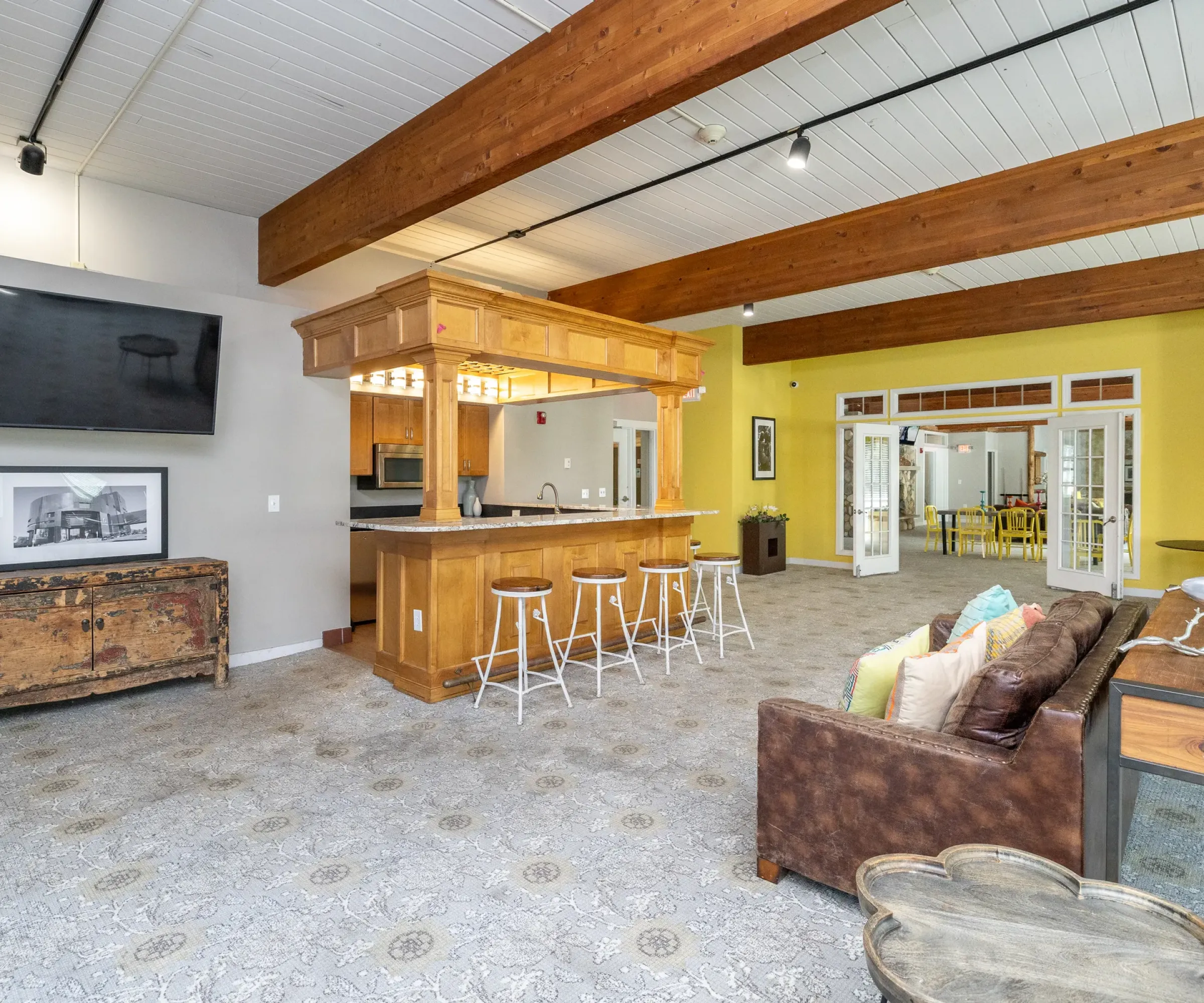 Aeon Affordable Homes Spacious room at Blooming Meadows South with a bar area, large TV, patterned floor, and cozy seating, featuring warm wood accents.