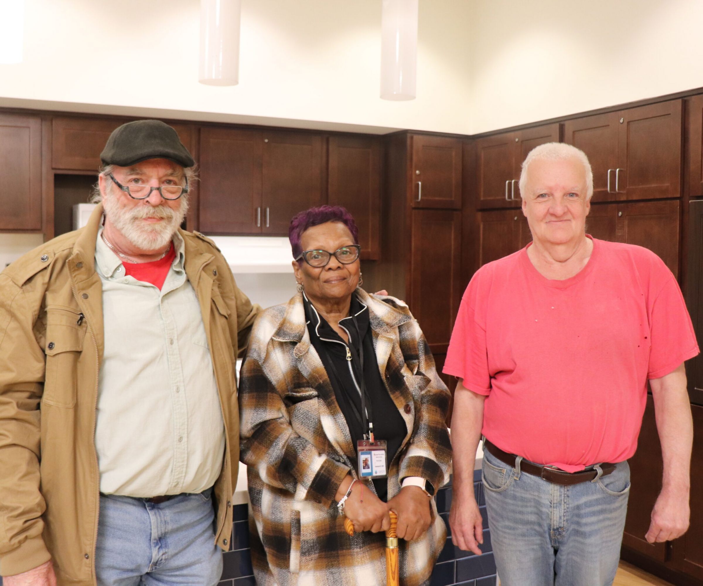 Aeon Affordable Homes Dan & Jim and a friend stand together in a kitchen, smiling at the camera, sharing a moment and their story.