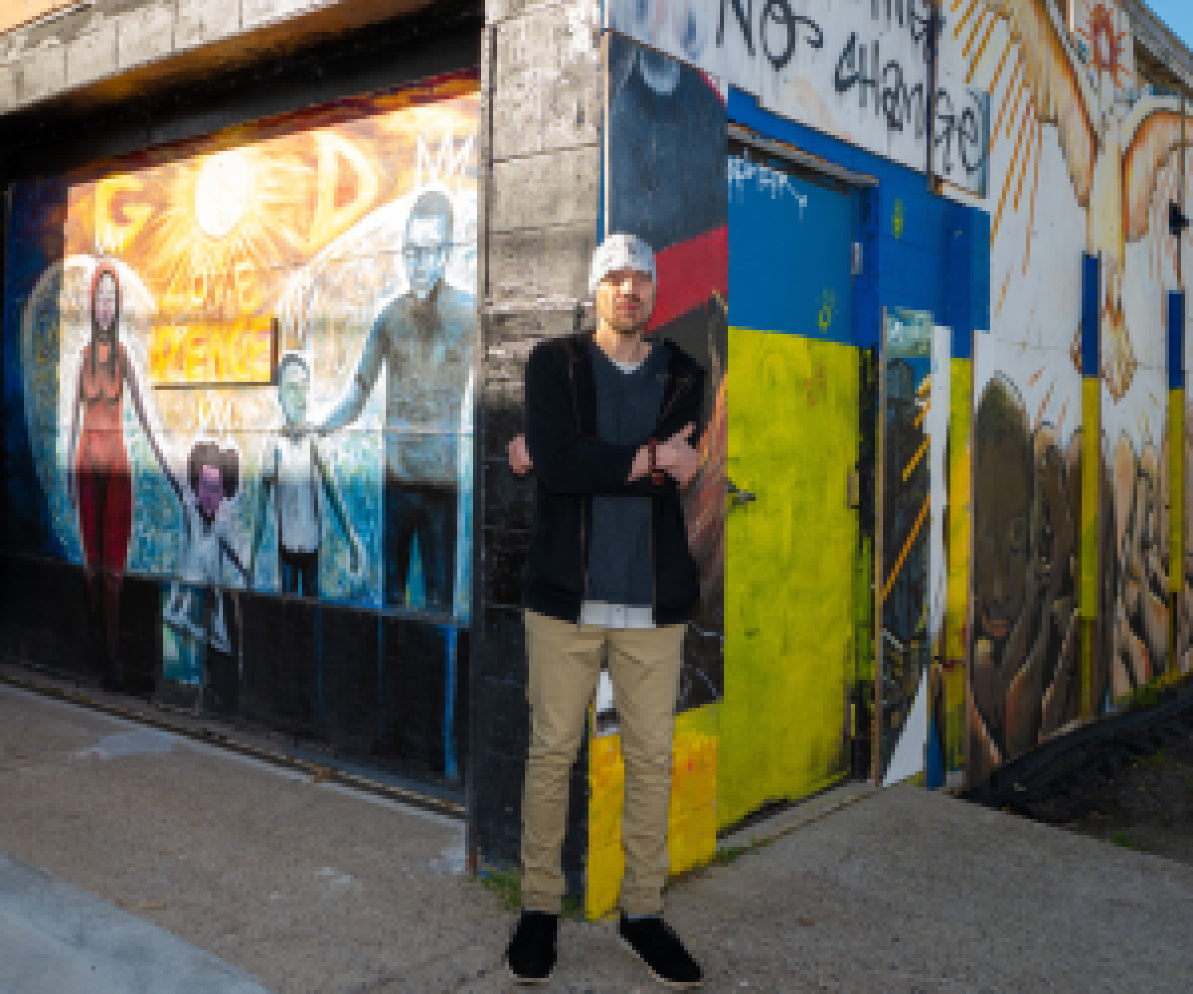 Aeon Affordable Homes resident Matthew in front of a building exterior showcasing his art