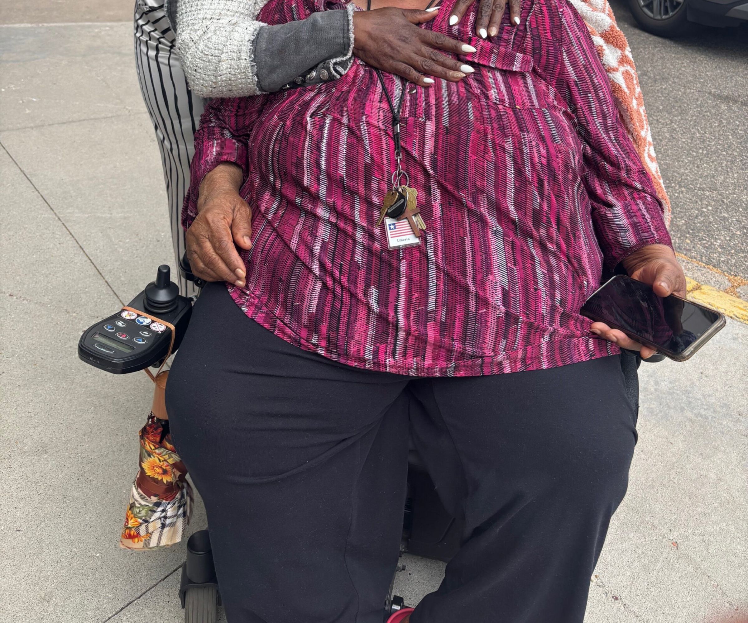 Aeon Affordable Homes A woman hugs Ms. Kumba, who is seated in a power wheelchair.