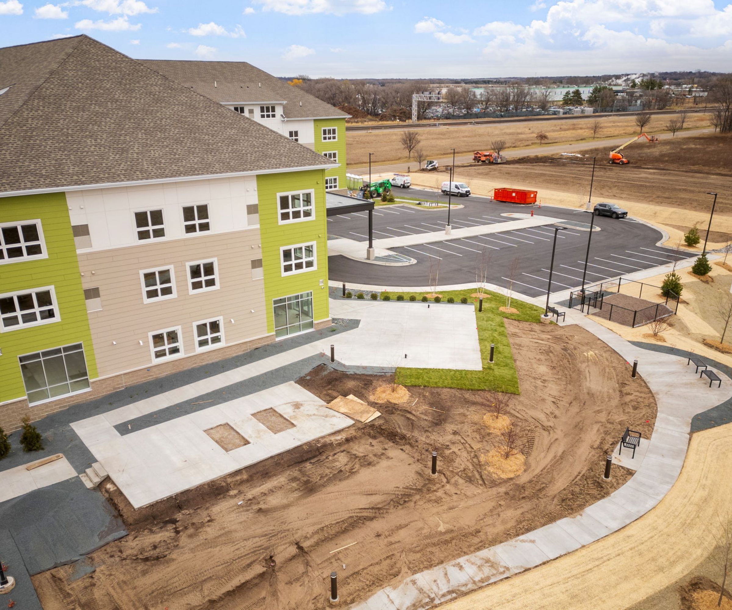 Aeon Affordable Homes and Community Aerial view of a new residential building offering affordable apartment homes, with surrounding construction and landscaping work in progress.