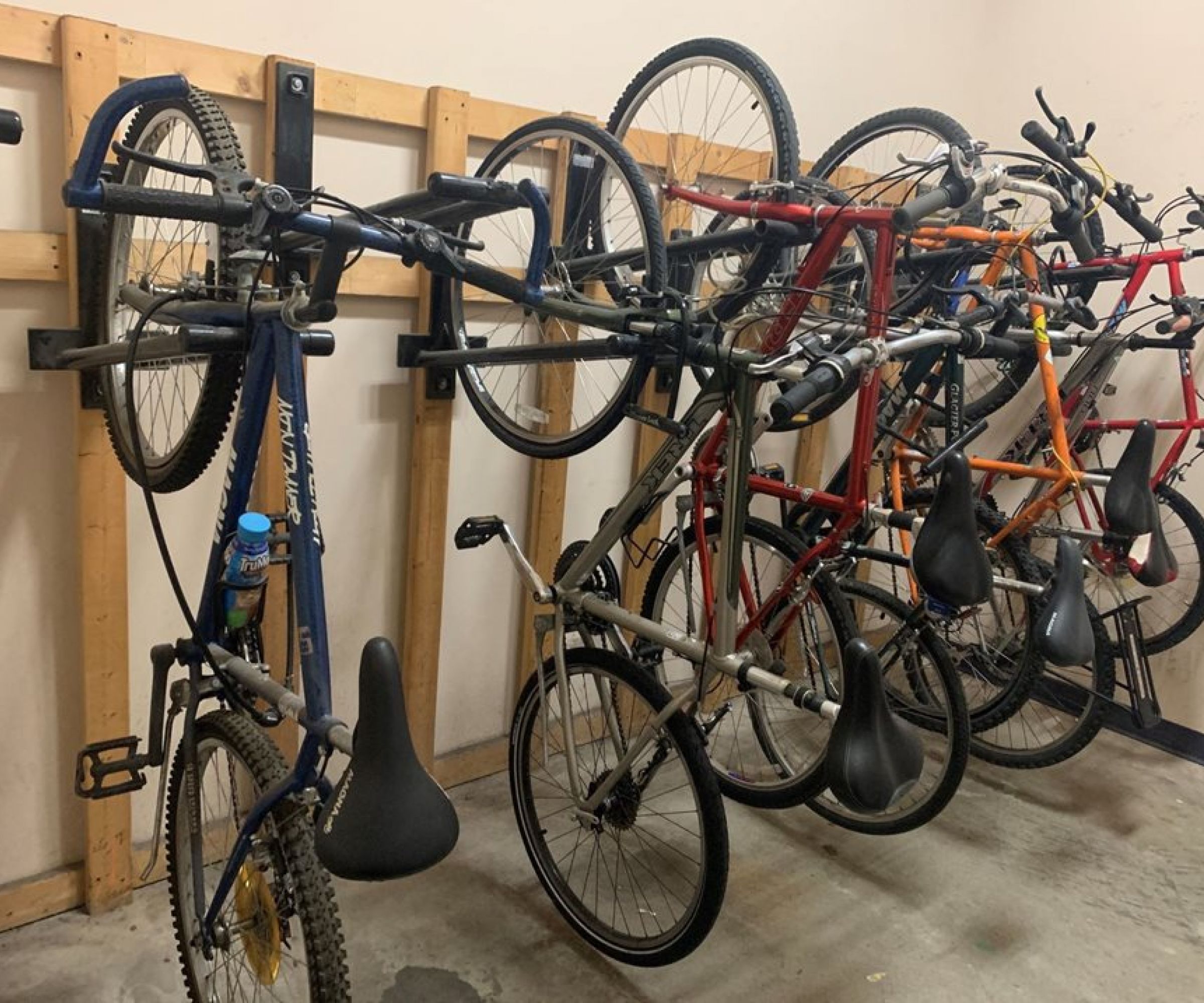 Aeon Affordable Homes and Community Bicycles hanging vertically on wall-mounted racks in the storage area of affordable apartment homes.