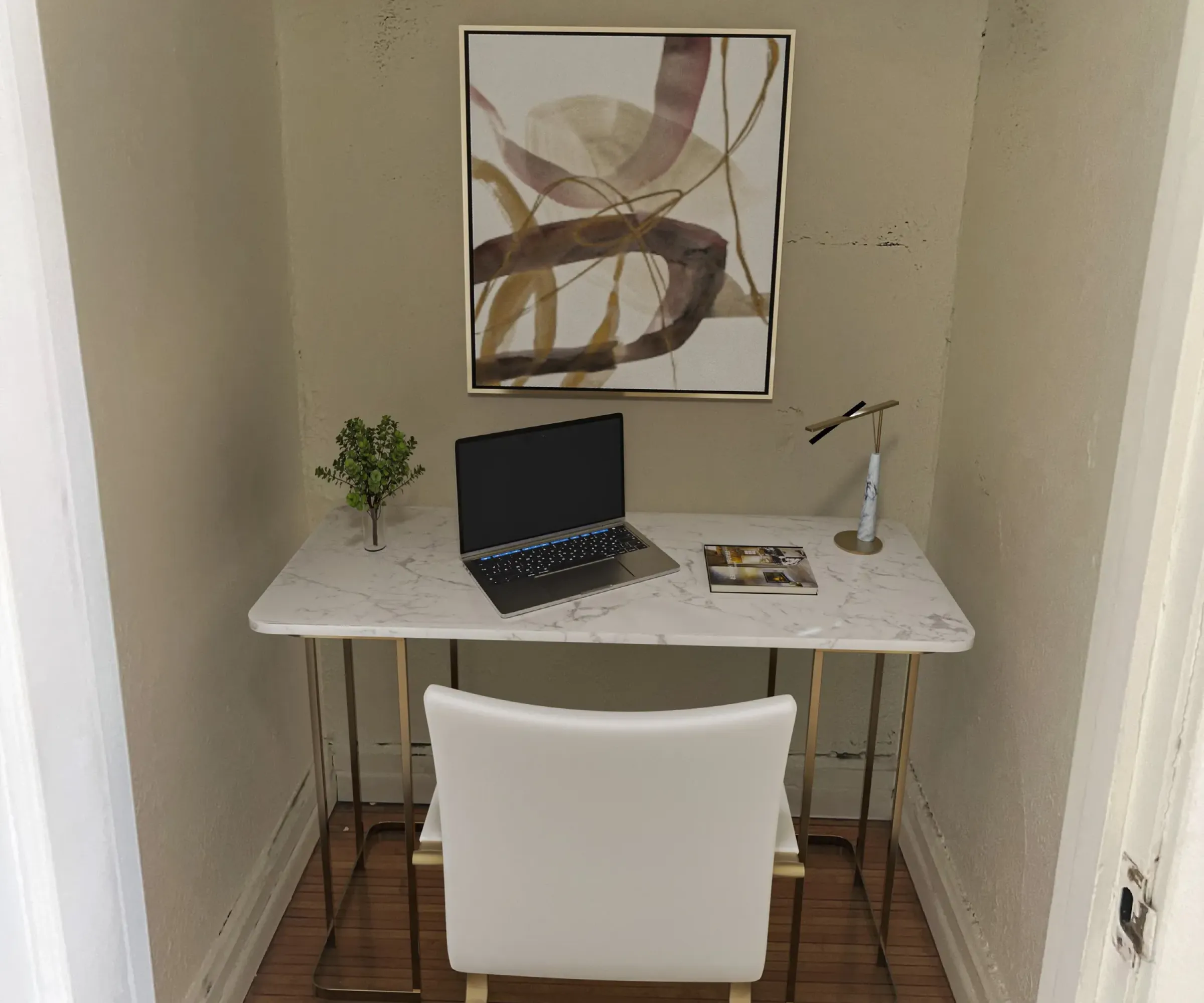 Aeon Affordable Homes and Community Compact home office in a closet, featuring a marble desk, laptop, lamp, chair, and abstract art above—perfect for affordable apartment homes.
