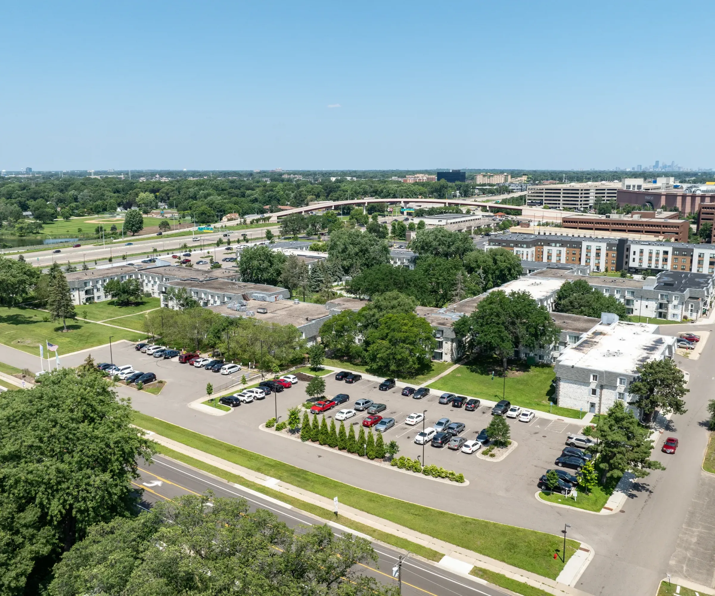 Aeon Affordable Homes Aerial view of Blooming Meadows South, with parking lots, roads, and buildings beautifully nestled among the trees.