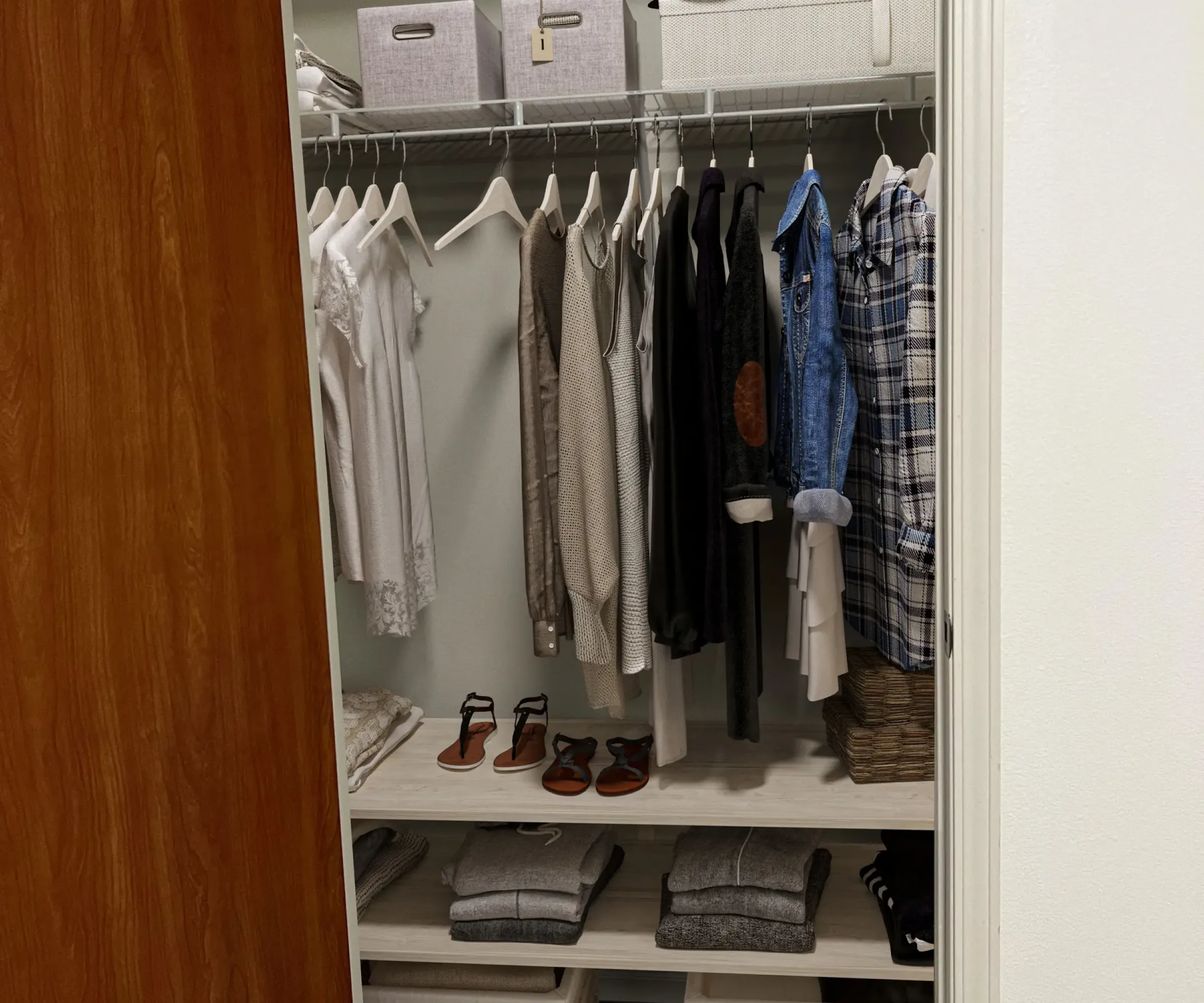Aeon Affordable Homes and Community A tidy closet in affordable apartment homes, with clothes on hangers, shoes on shelves, and storage boxes.