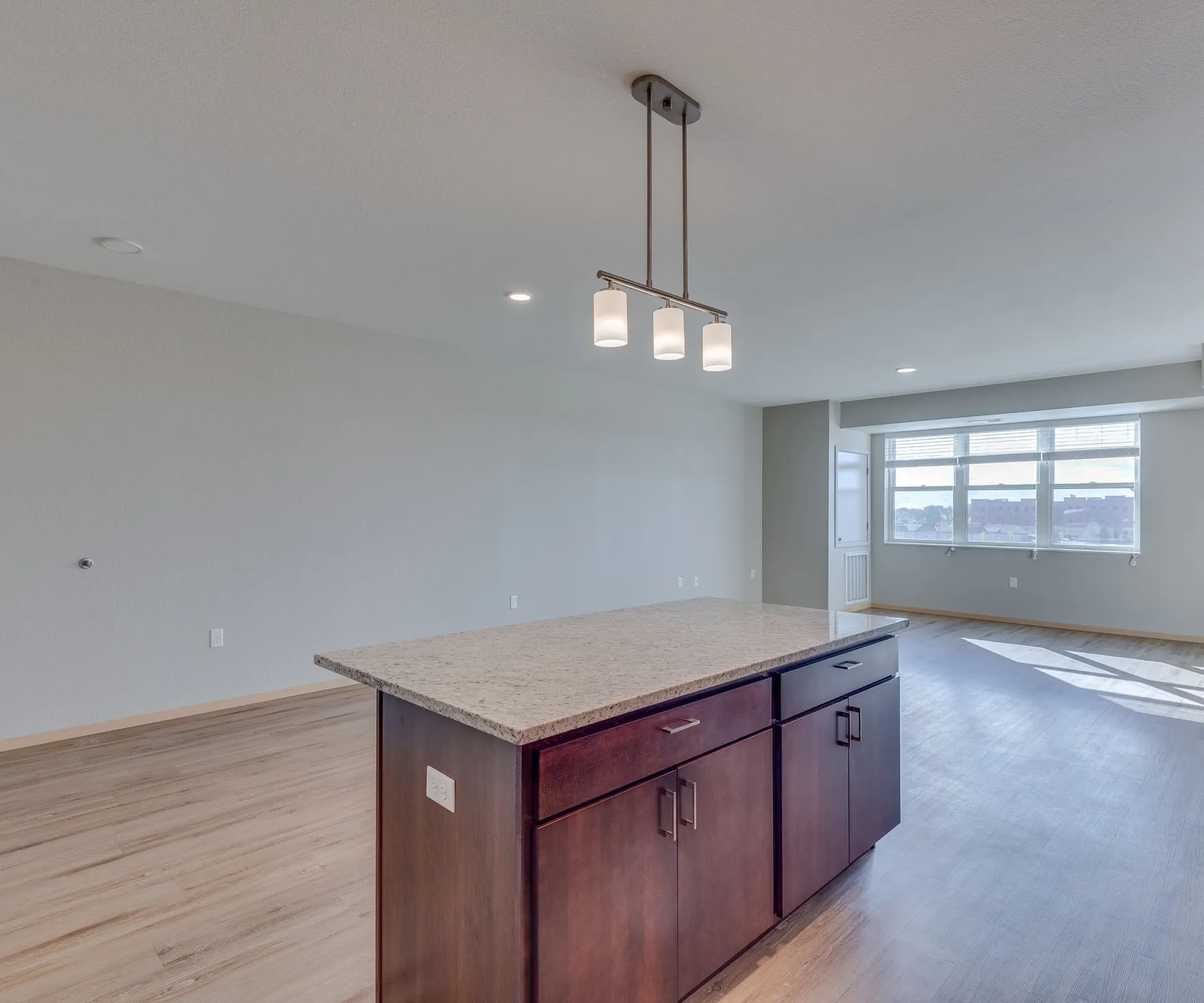Aeon Affordable Homes and Community Modern, affordable apartment home with wooden floors, a central kitchen island, and large windows.