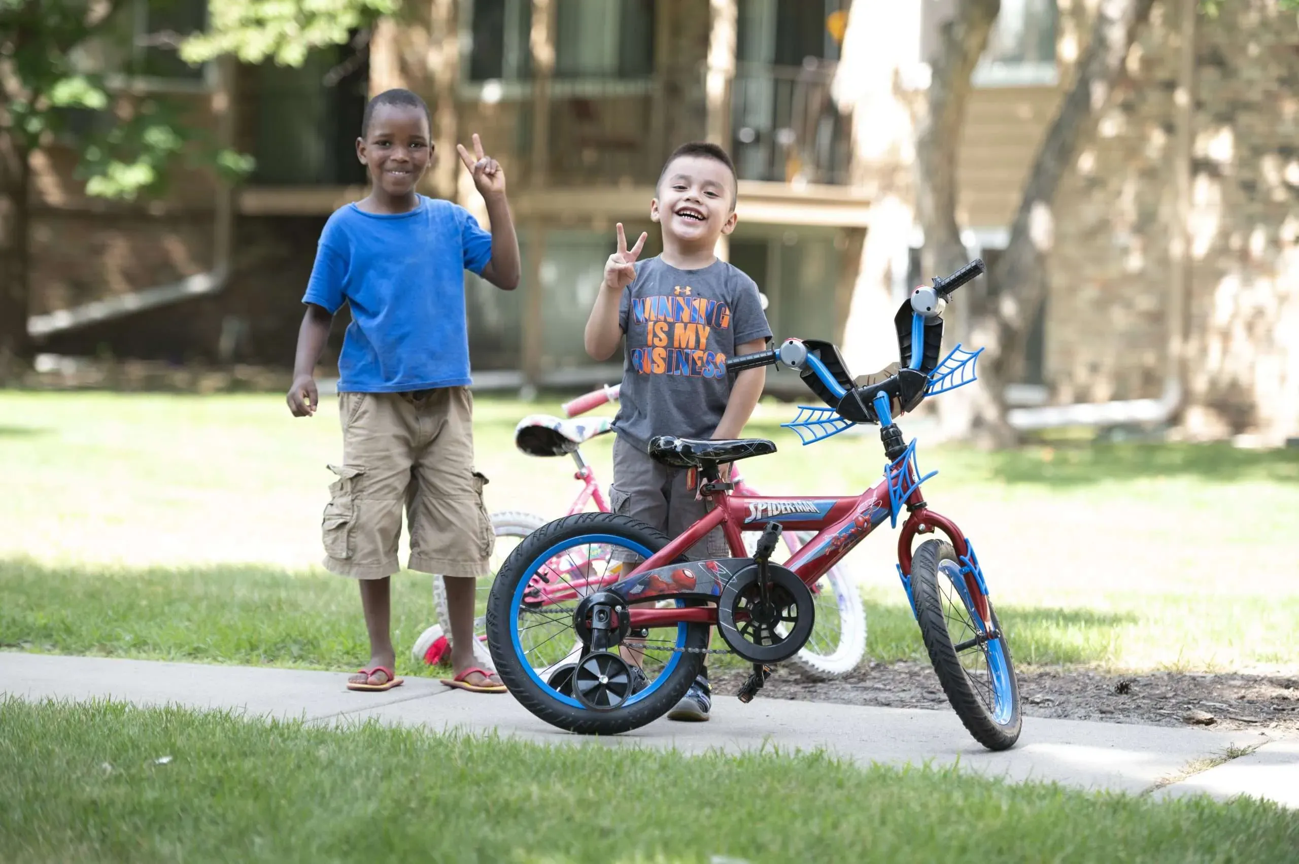 Aeon Affordable Homes with two young boys playing outside an apartment building with a bike