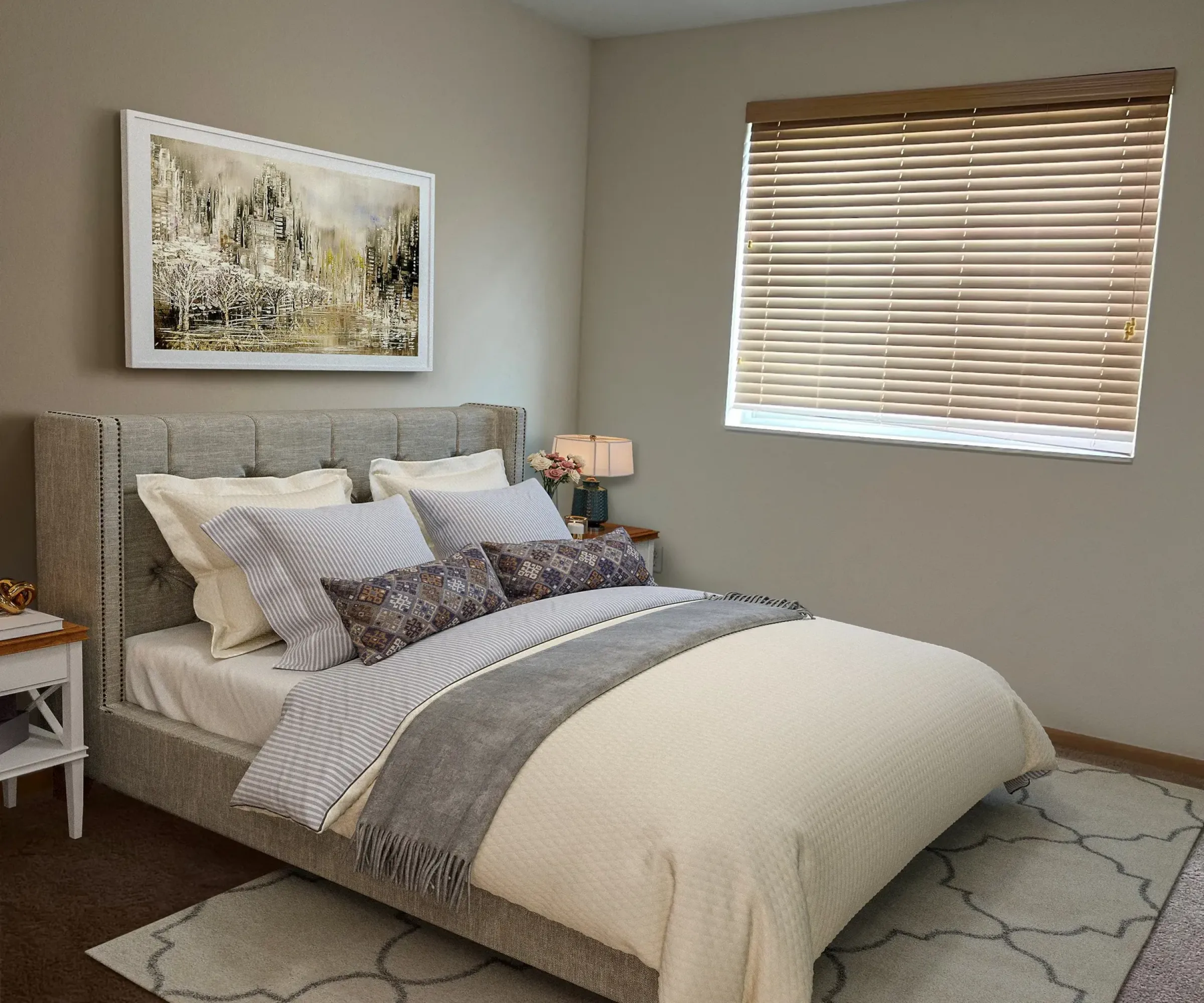 Aeon Affordable Homes and Community Cozy bedroom in affordable apartment homes, featuring a neatly made bed, decorative pillows, wall art, and a window with blinds.