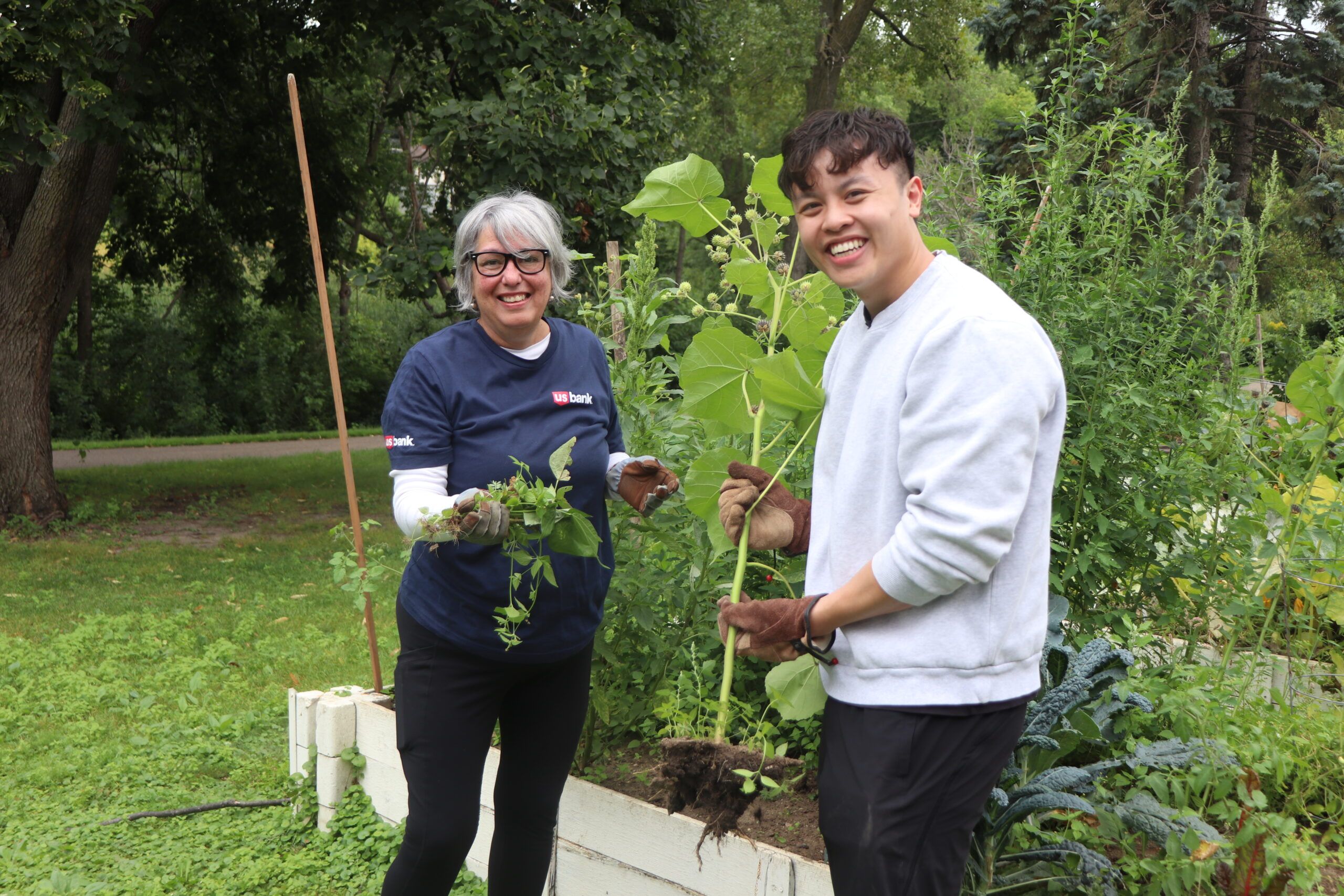 Aeon Affordable Homes Two people smiling and gardening together in a lush, green outdoor garden bed.