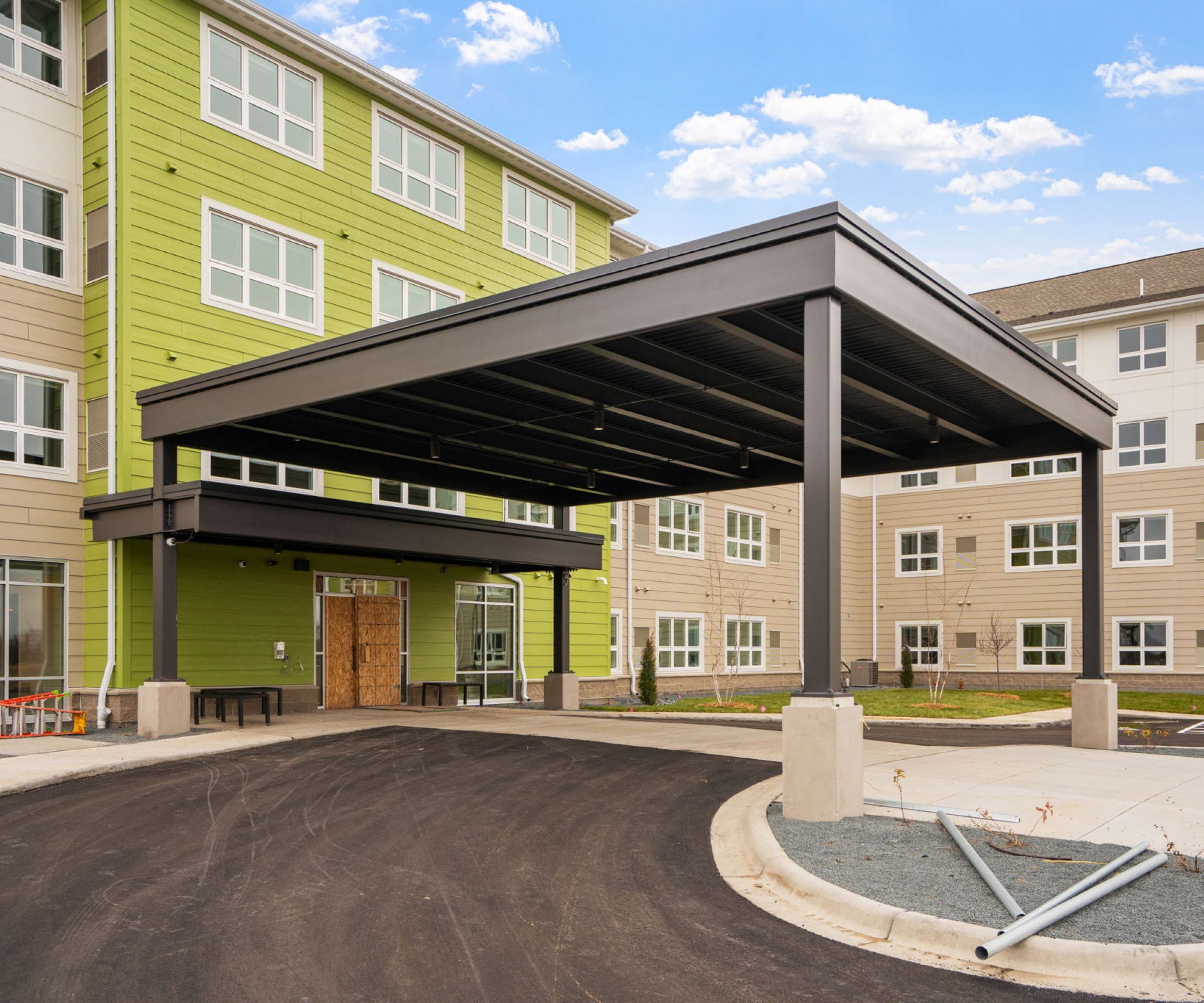 Aeon Affordable Homes and Community Modern multi-story building with a green facade and large entrance canopy, offering affordable apartment homes.
