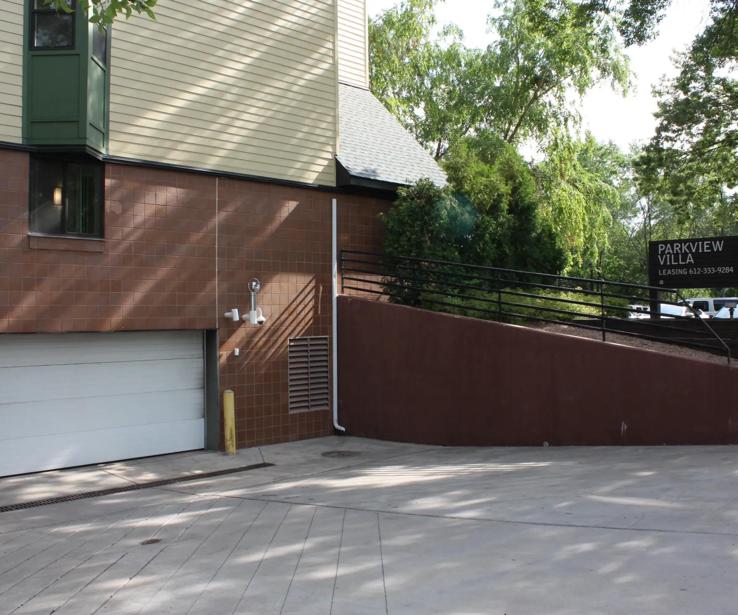 Aeon Affordable Homes and Community Building exterior with a garage, ramp, and a sign reading "Parkview Villa Leasing & Info 965." Trees in the background offer affordable apartment homes.
