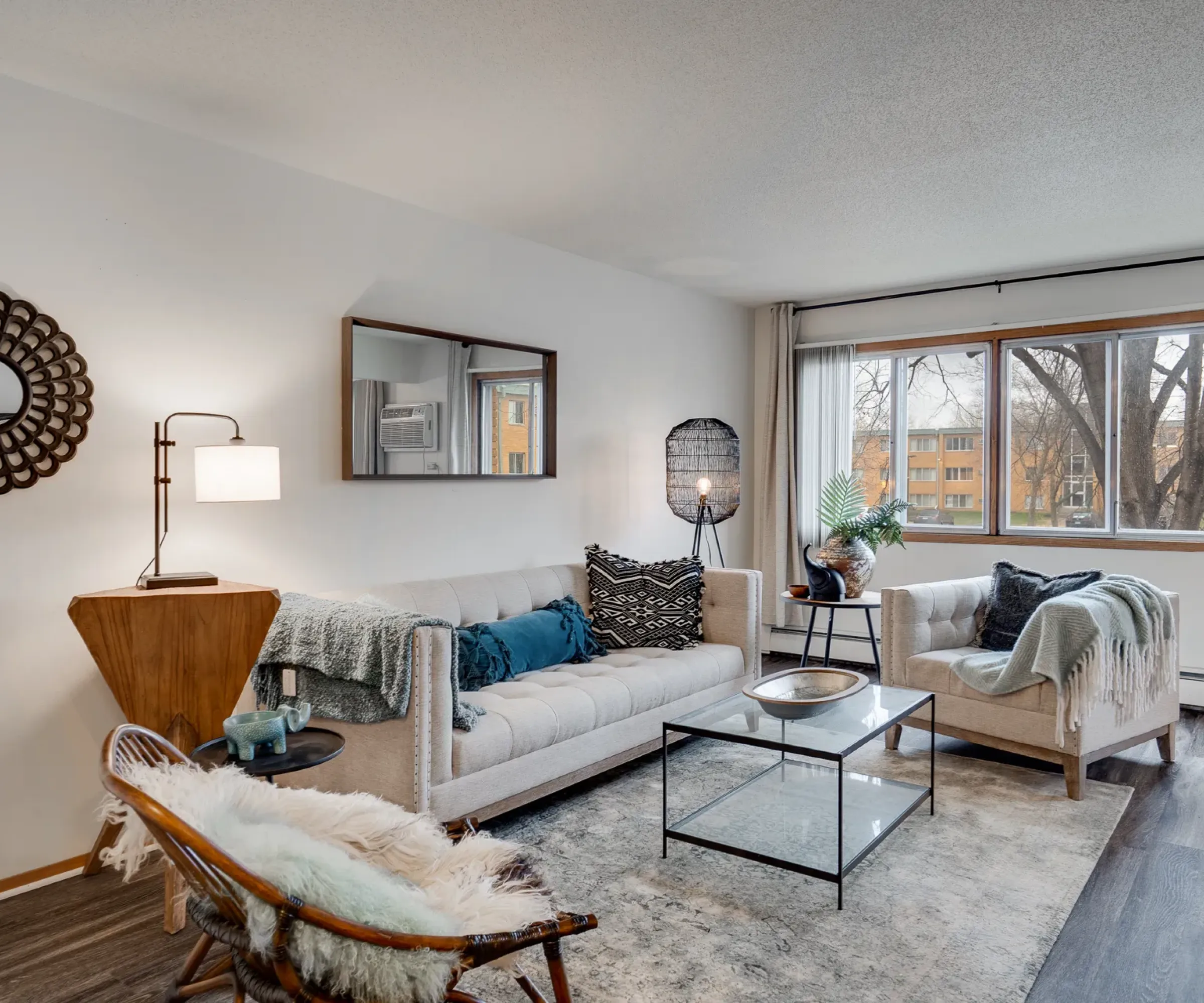 Aeon Affordable Homes Modern living room with beige sofas, glass coffee table, large window, and decorative accents.