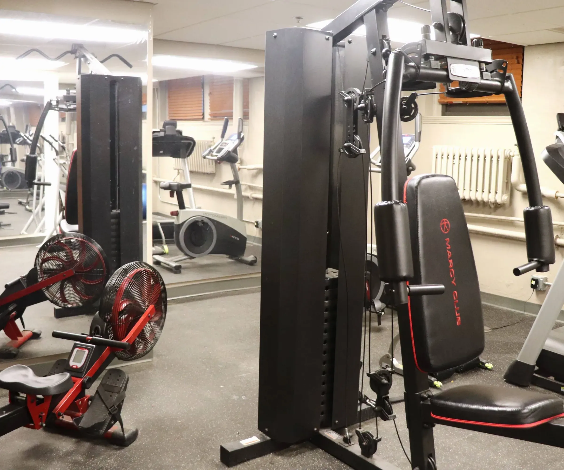 Aeon Affordable Homes and Community Affordable apartment homes featuring a fitness room with gym equipment, including a rowing machine, weight machine, exercise bike, and treadmill.