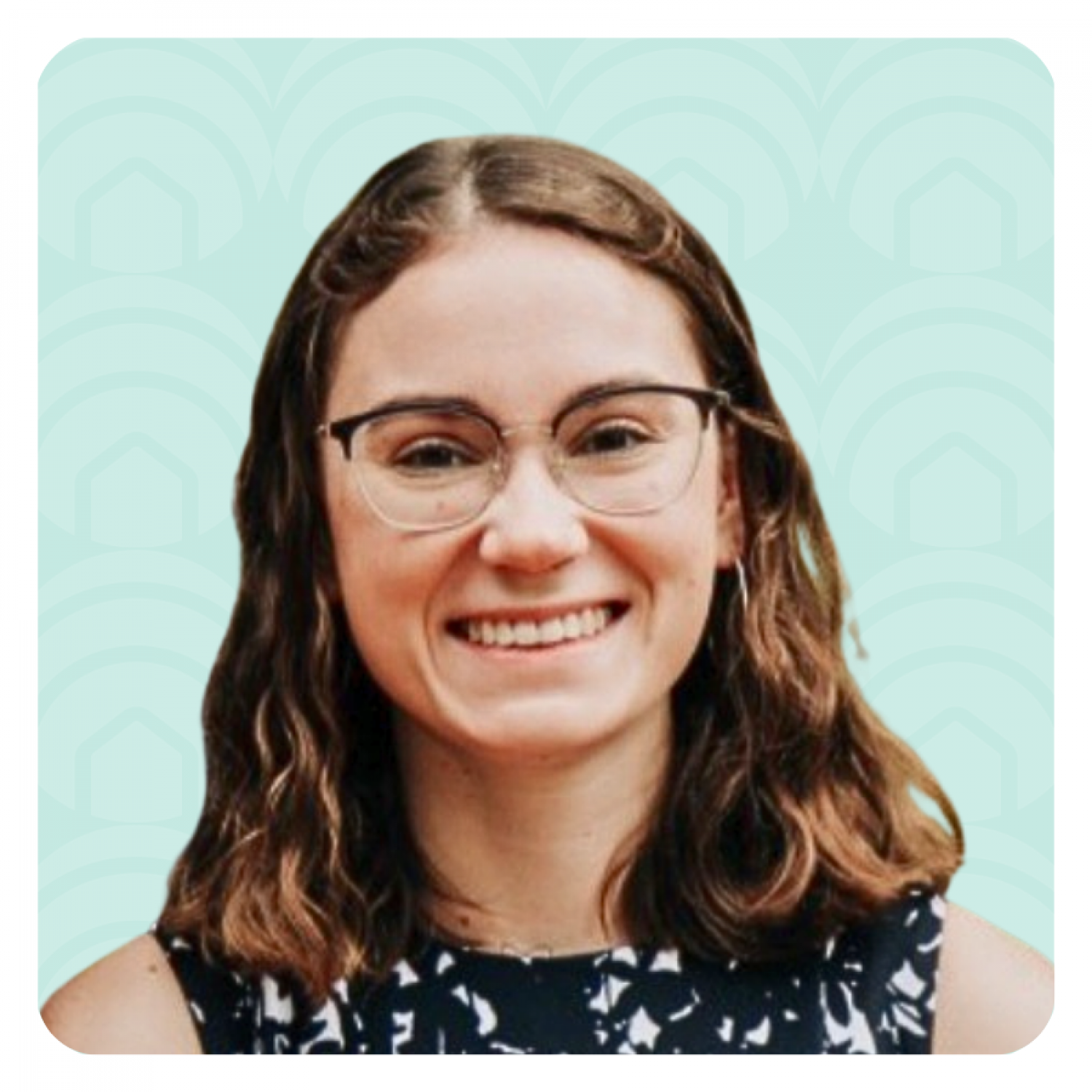 Aeon Affordable Homes Smiling woman with glasses and wavy brown hair, possibly Autumn Delong Rodgers, wears a patterned top against a teal patterned background.