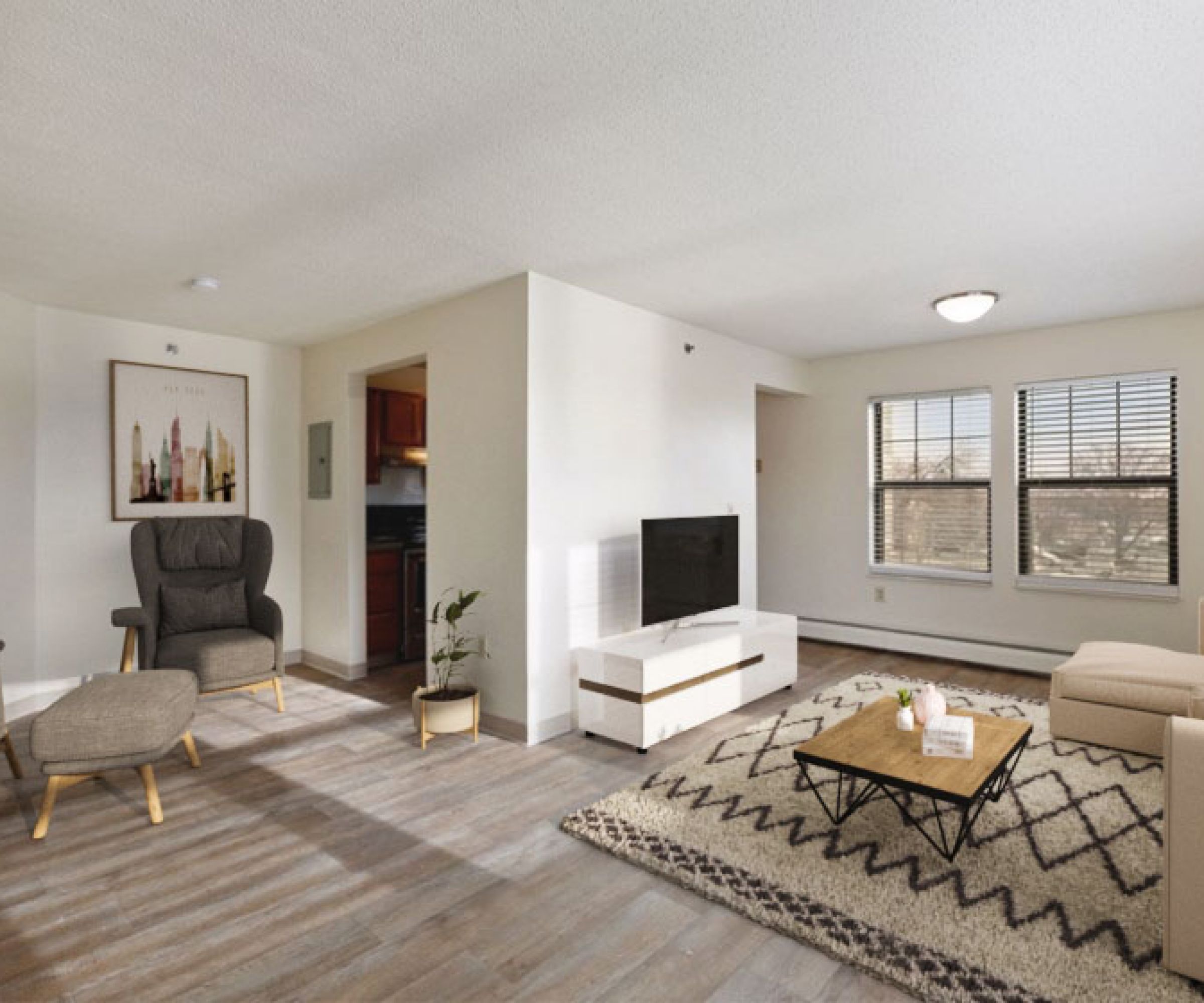 Aeon Affordable Homes and Community Minimalist living room in affordable apartment homes with light walls, wooden floor, beige sofa, TV, armchair, geometric rug, and large windows.