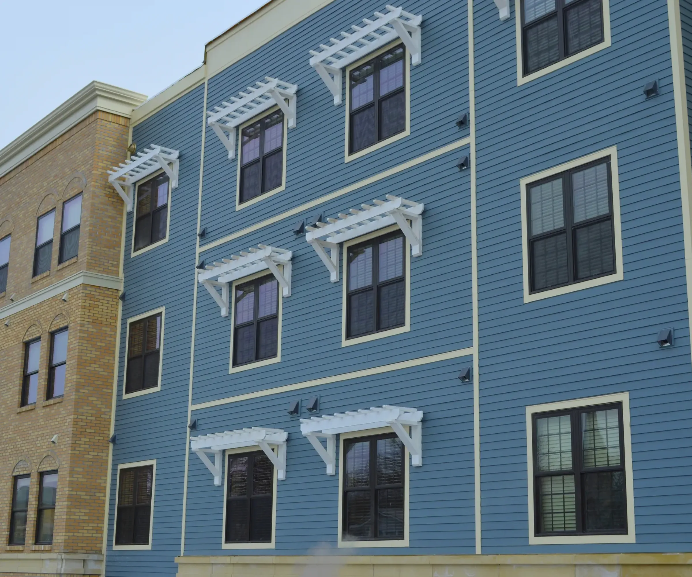 Aeon Affordable Homes and Community A brick and blue building with white trim, showcasing modern, affordable apartment homes.