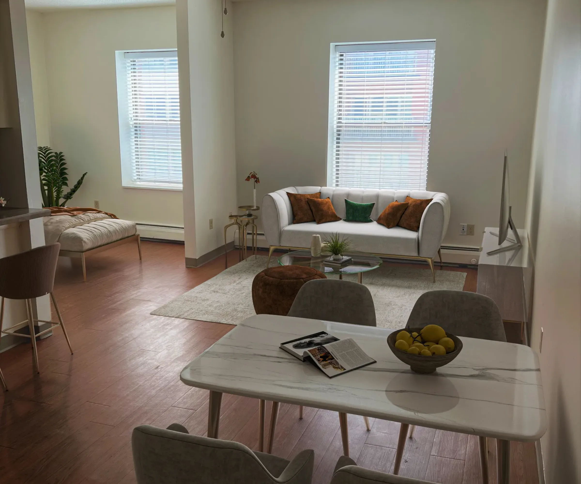 Aeon Affordable Homes and Community Modern living room in affordable apartment homes with a white sofa, brown cushions, dining table, and ceiling fan. Bright with natural light.