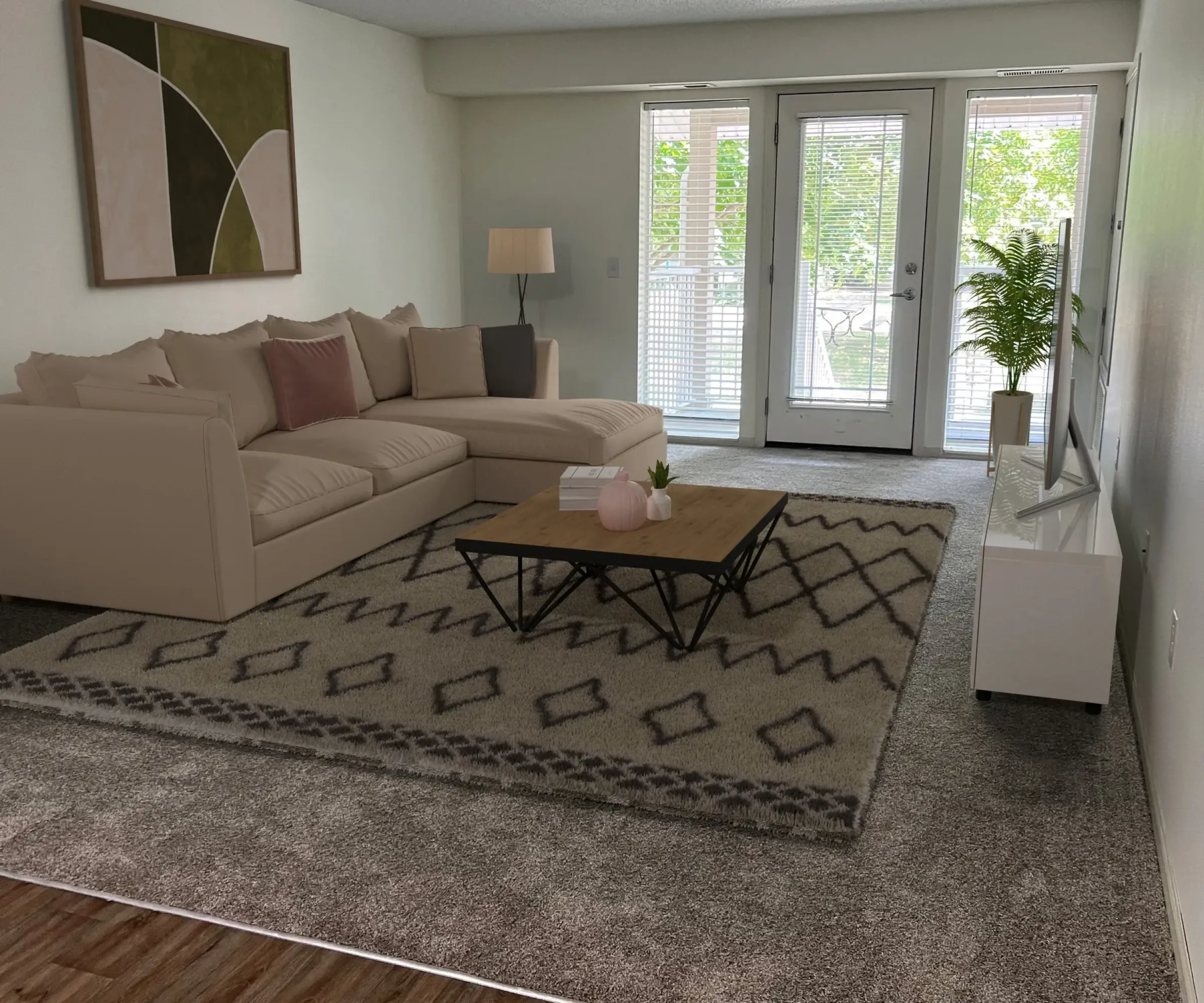 Aeon Affordable Homes and Community A cozy living room in affordable apartment homes, featuring a beige sofa, patterned rug, coffee table, lamp, TV, wall art, and glass doors to the outside.