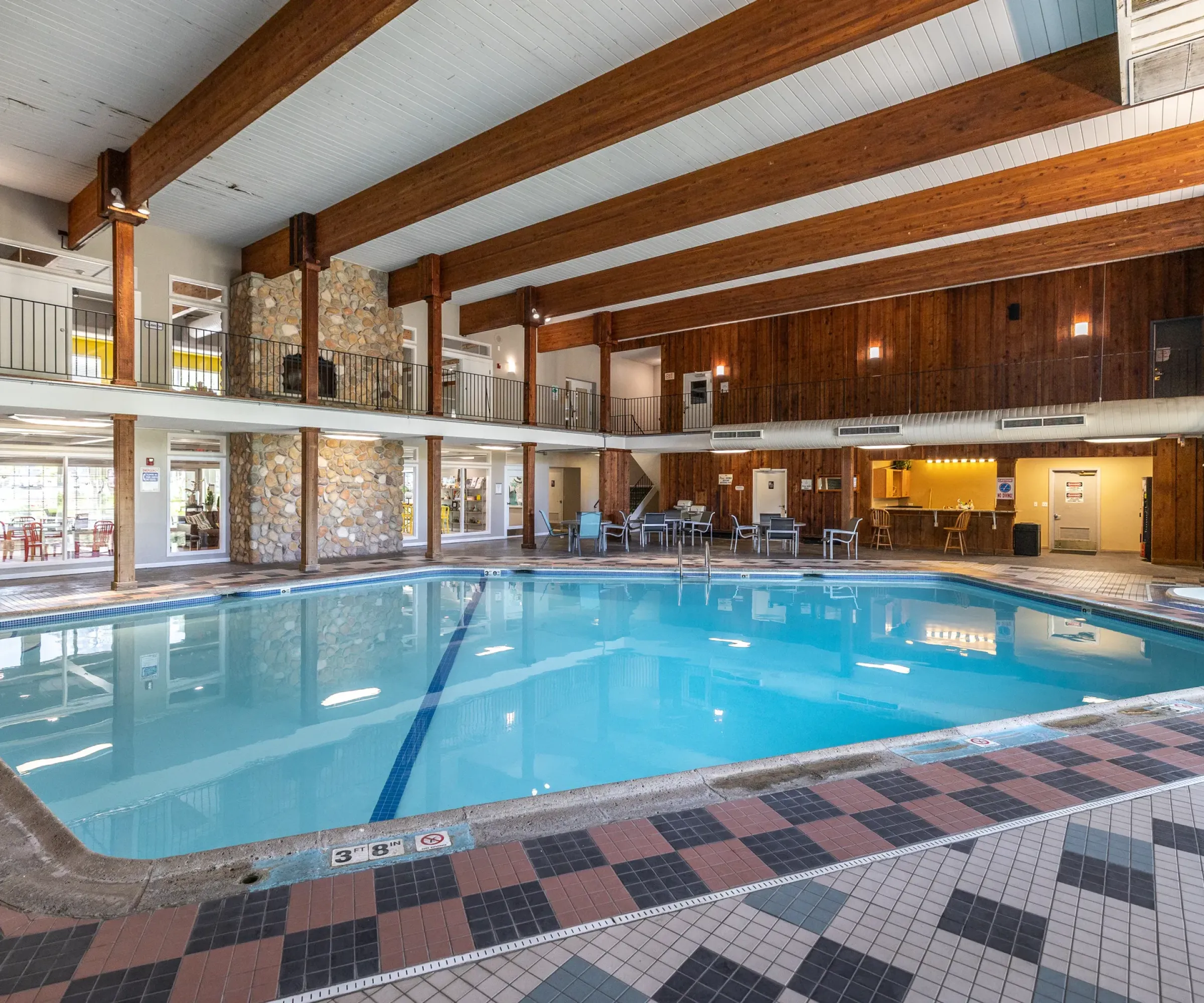 Aeon Affordable Homes Indoor pool area with wooden beams and a stone feature wall, offering a serene escape reminiscent of the blooming meadows in the South.