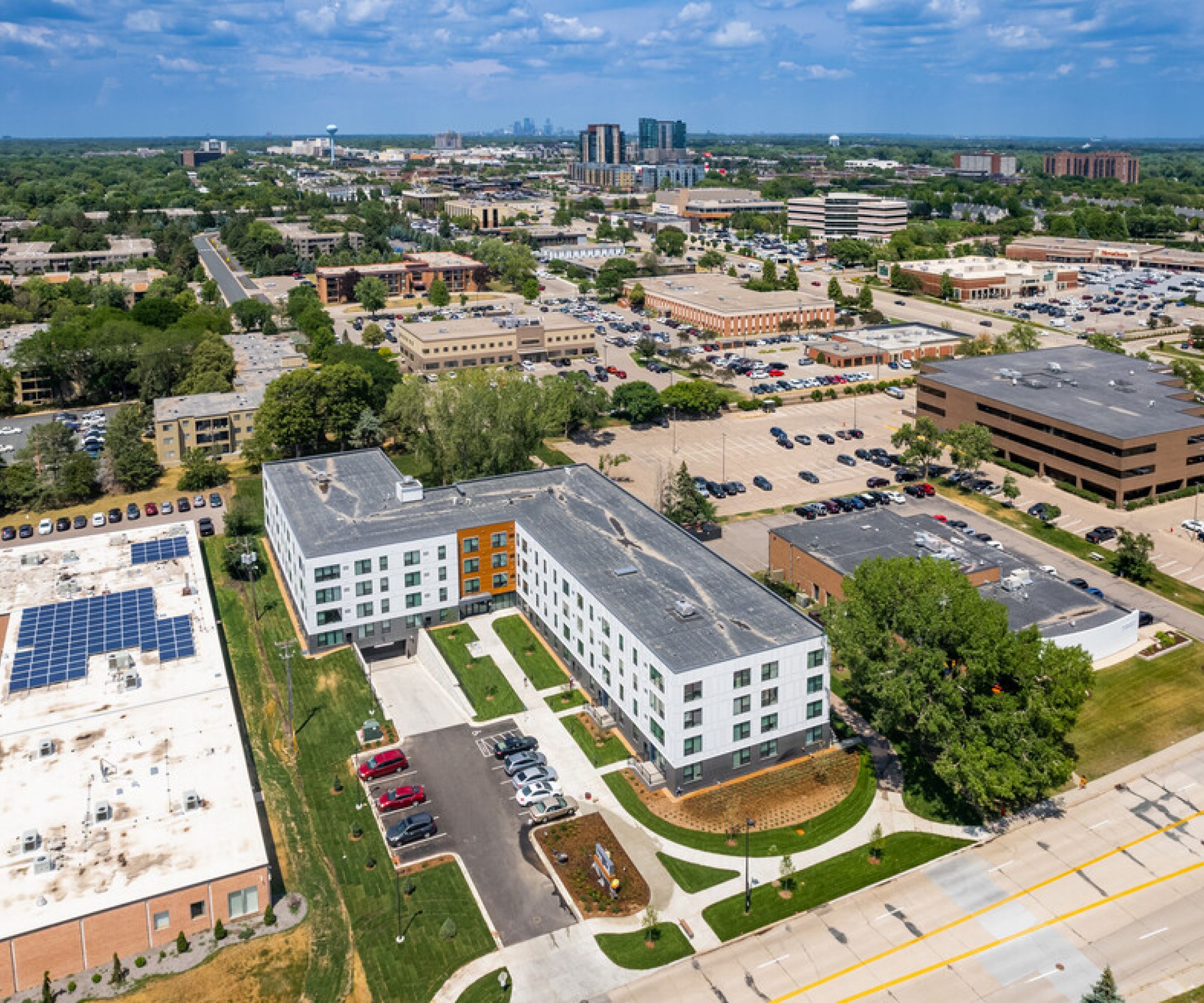 Aeon Affordable Homes and Community Aerial view of a suburban area, showcasing roads and affordable apartment homes under a partly cloudy sky.