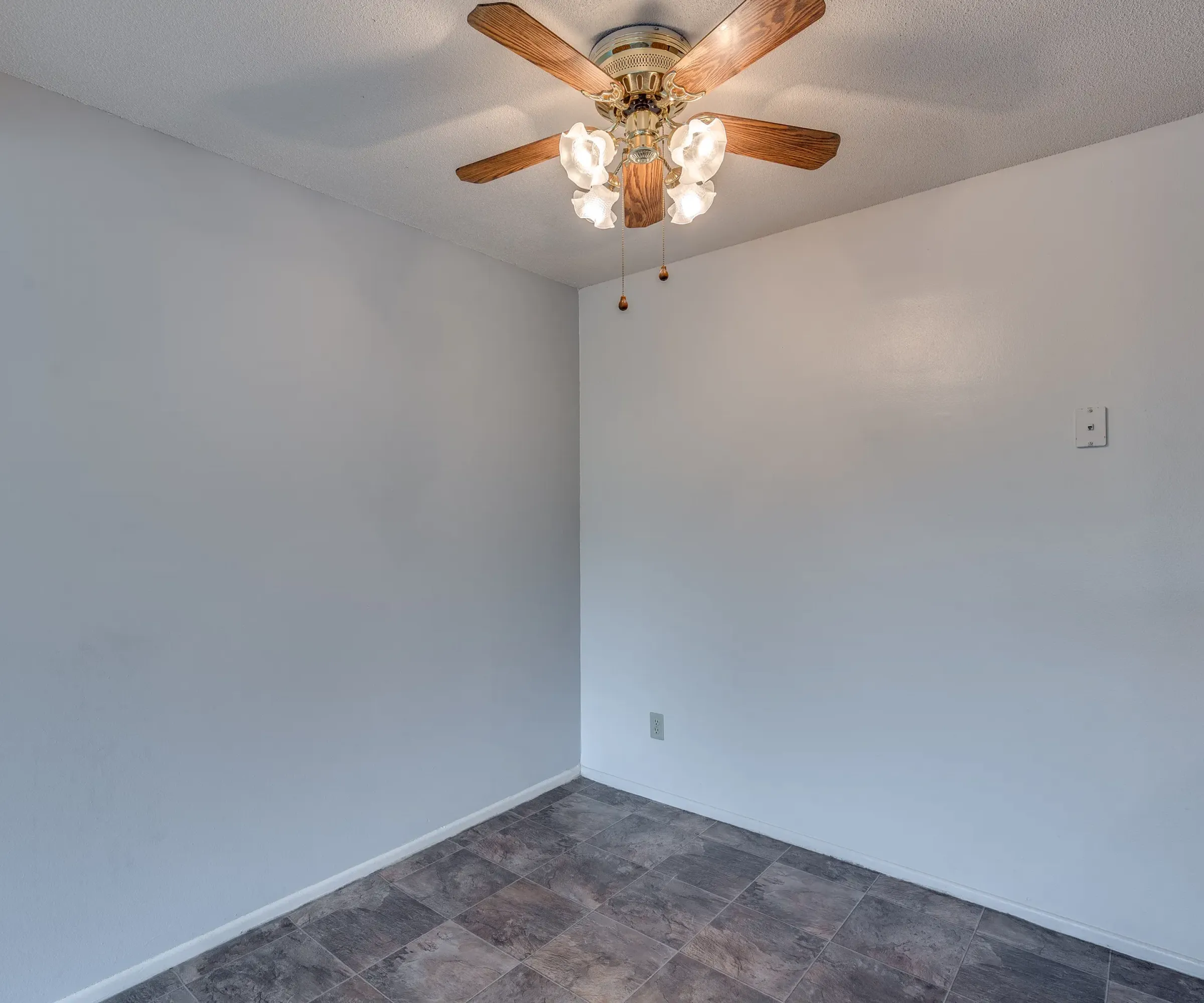 Aeon Affordable Homes and Community Affordable apartment homes featuring an empty room with white walls, tiled floor, and a ceiling fan with lights.