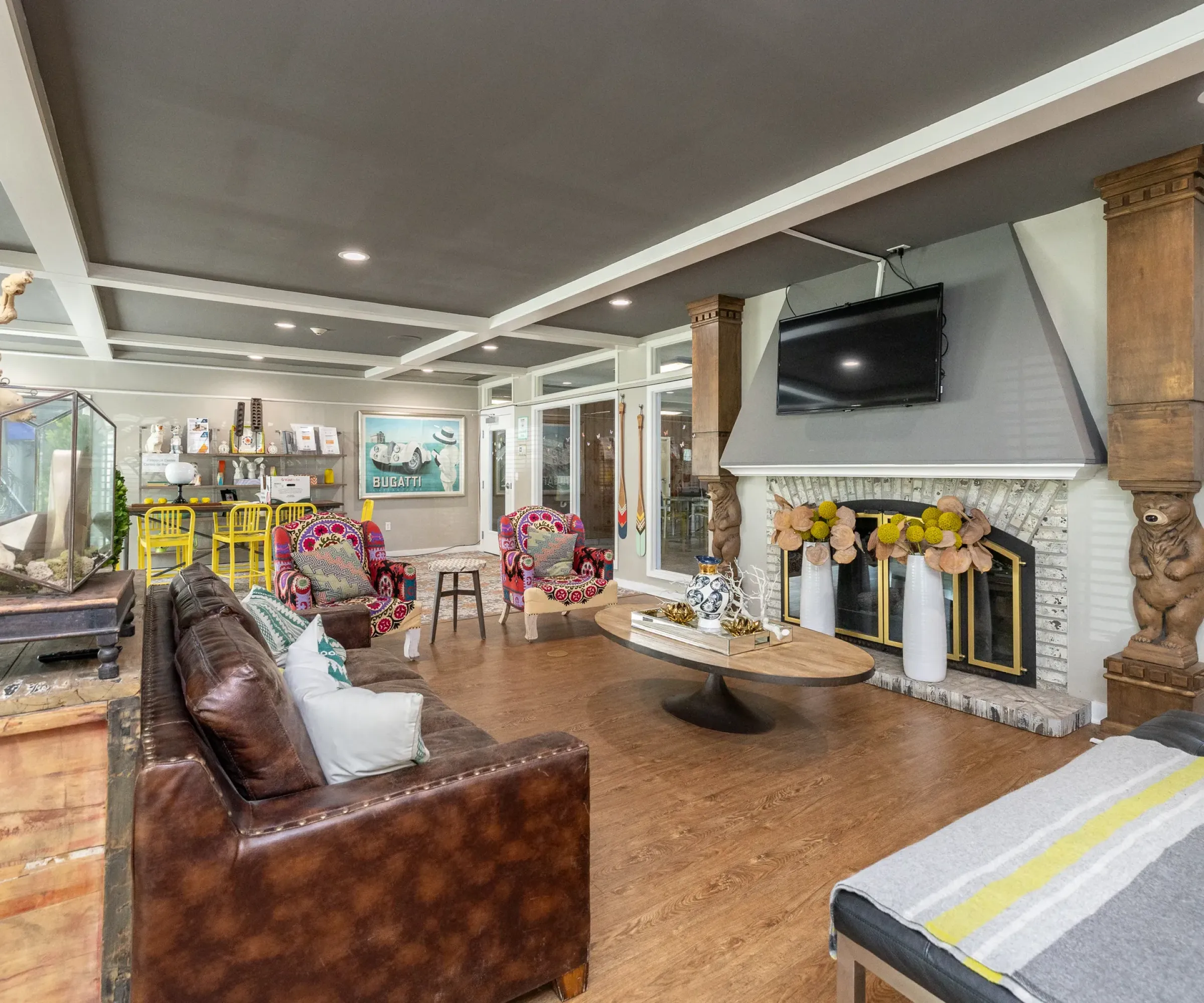 Aeon Affordable Homes Spacious living room in Blooming Meadows South with a brown leather sofa, colorful armchairs, fireplace, and wall-mounted TV.