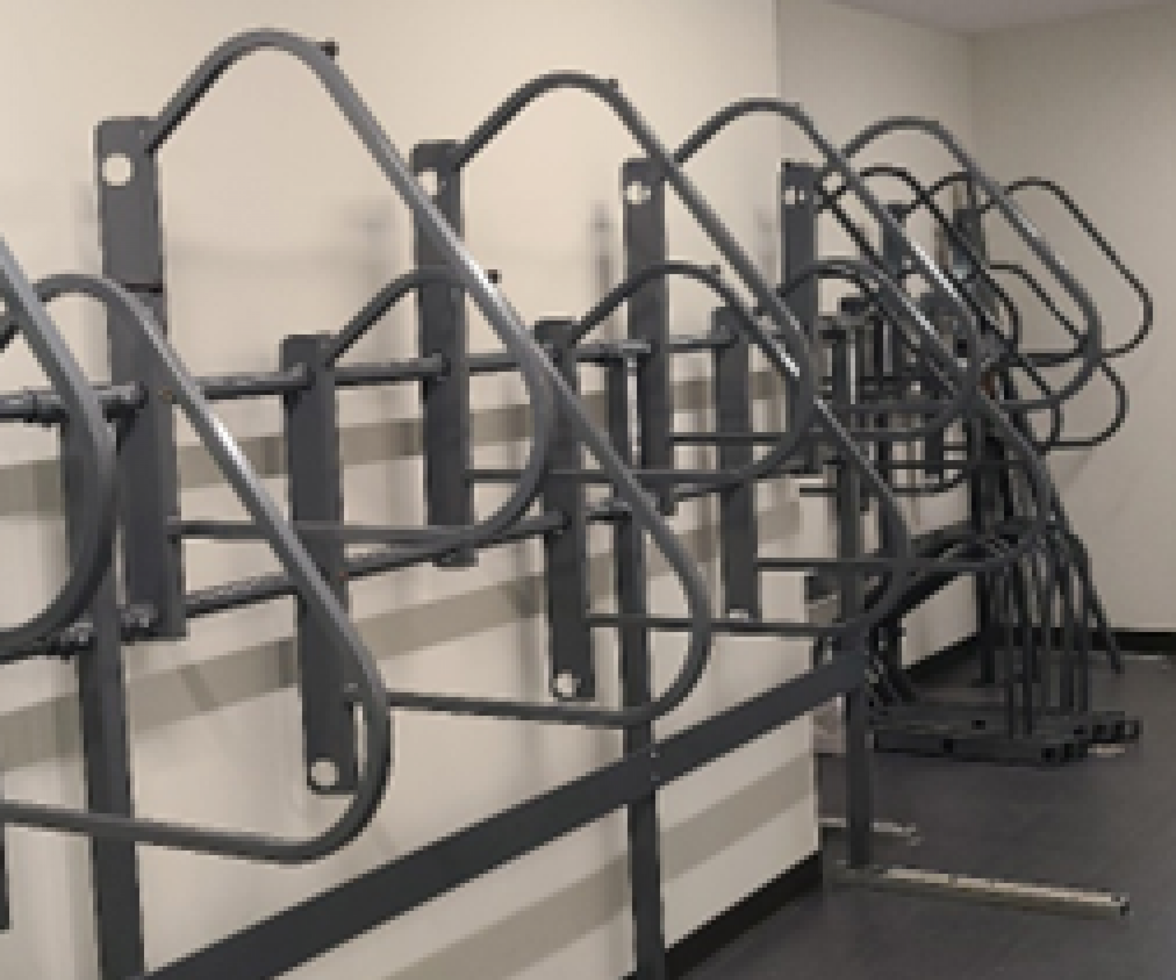 Aeon Affordable Homes and Community Affordable apartment homes featuring wall-mounted metal bike racks in an empty room with a gray floor.
