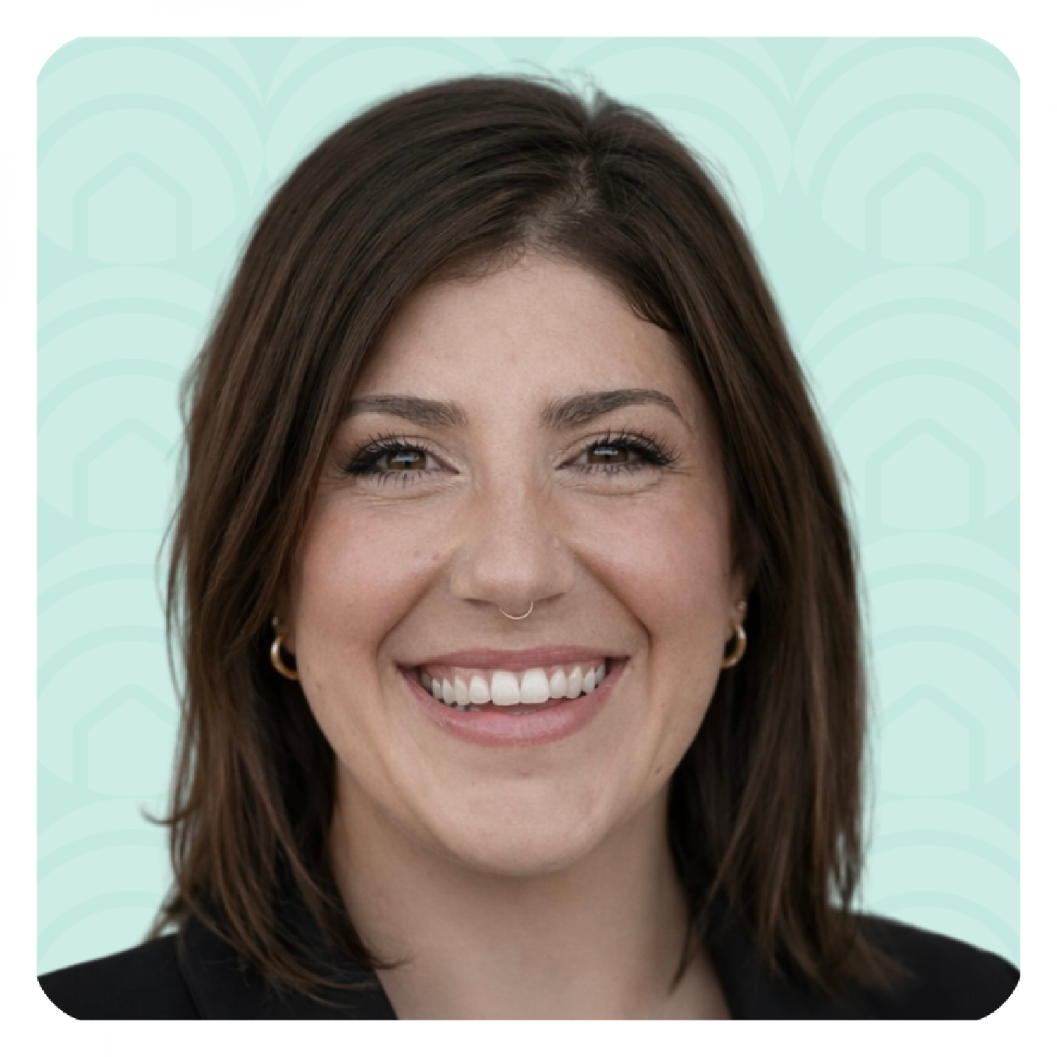 Aeon Affordable Homes Smiling woman with brown hair and a nose ring, wearing a black top, against a light blue patterned background.