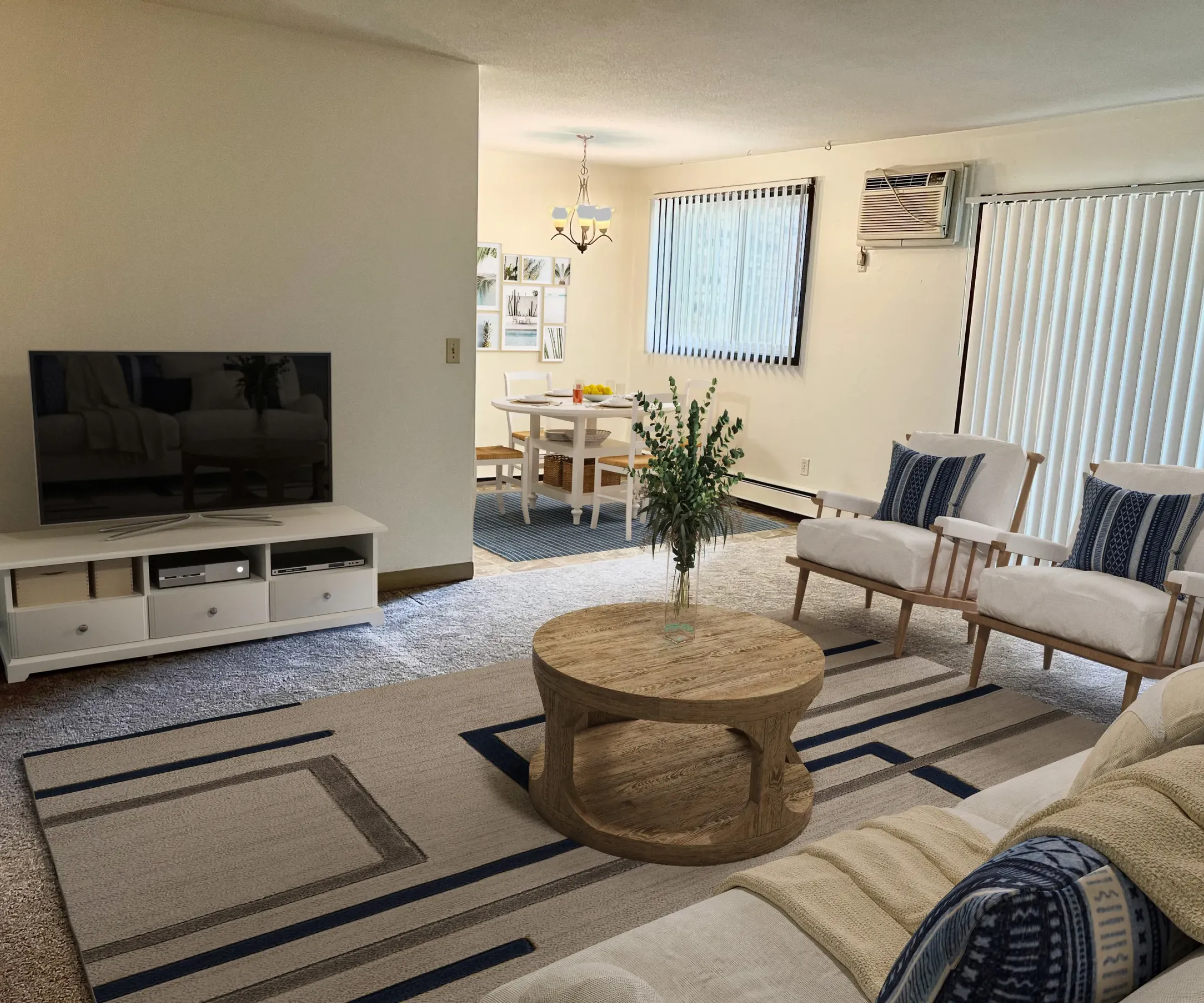 Aeon Affordable Homes and Community Cozy living room in affordable apartment homes with TV, wooden coffee table, chairs, and a view of the dining area.