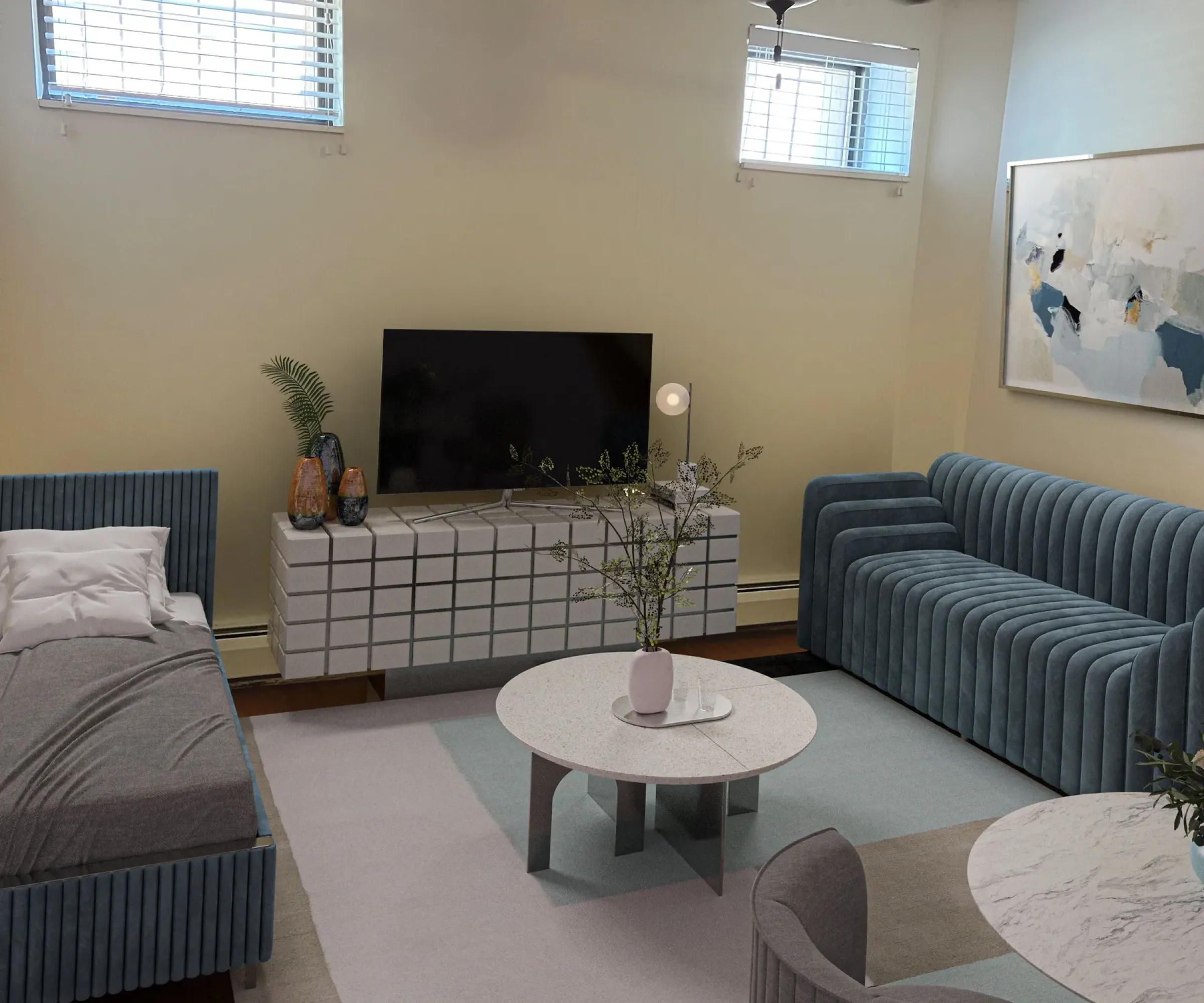 Aeon Affordable Homes and Community A cozy living room in affordable apartment homes, featuring a TV, blue sofas, a bed, round coffee tables, abstract art, and ceiling fan.