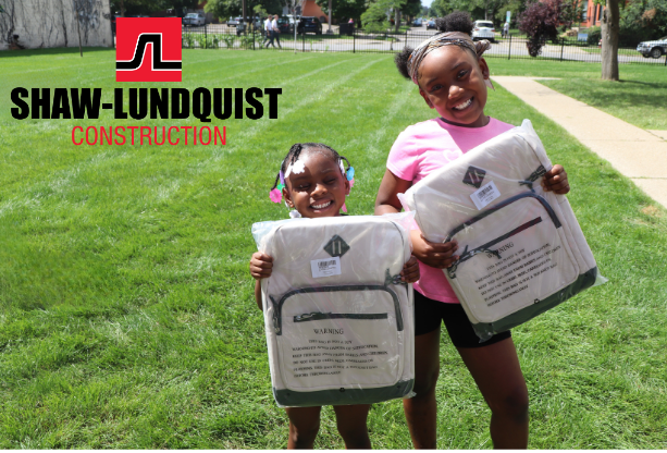 Aeon Affordable Homes Two smiling girls with backpacks in a park near a Shaw-Lundquist Construction logo, building stronger communities together.
