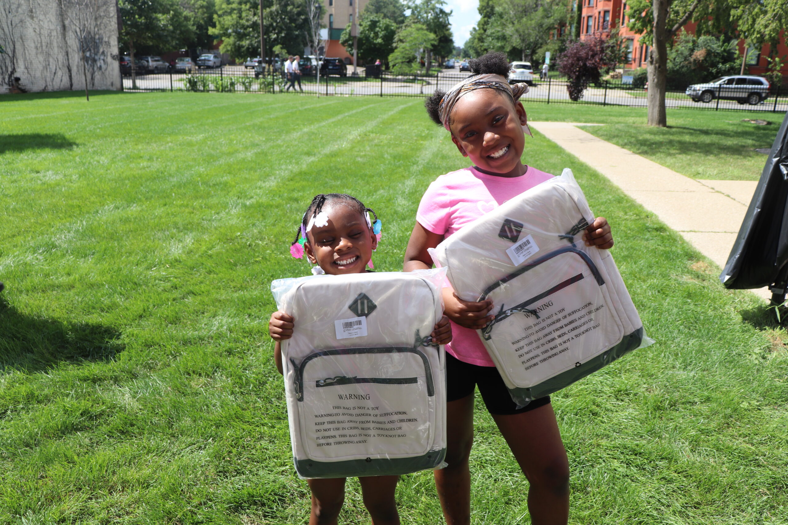 Two children holding donated backpacks