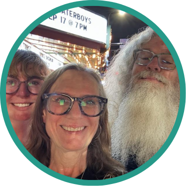 Aeon Affordable Homes Three smiling Aeon staff with glasses pose for a selfie at night in front of a lit theater marquee, celebrating giving back.