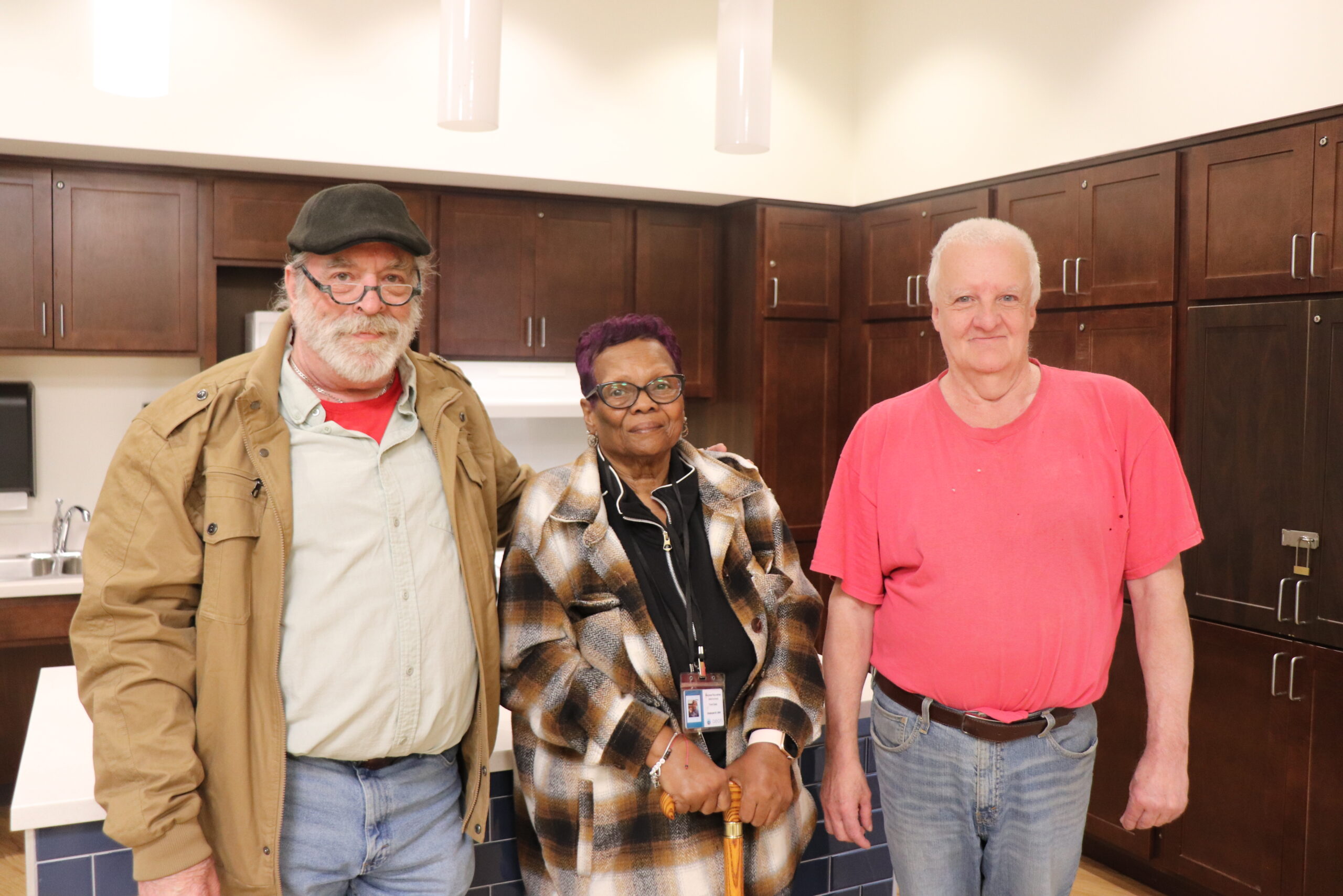 Aeon Affordable Homes Dan & Jim and a friend stand together in a kitchen, smiling at the camera, sharing a moment and their story.