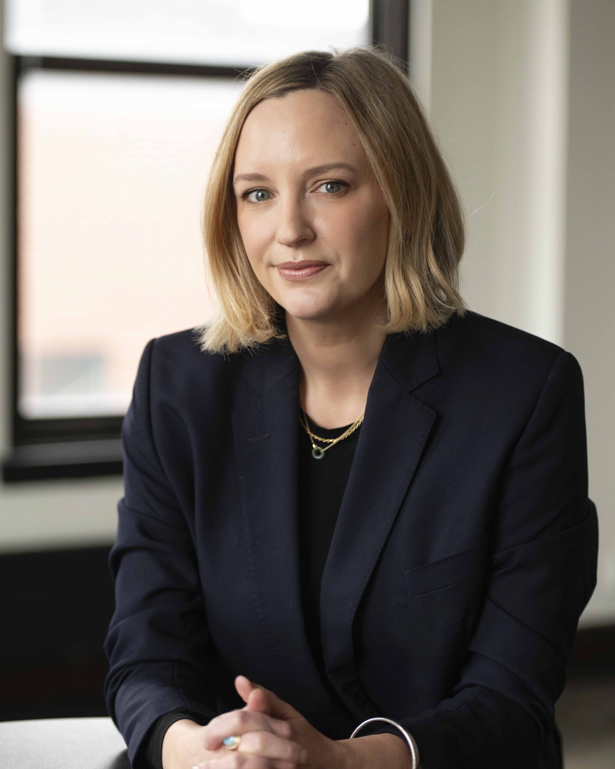 Aeon Affordable Homes Rachel Robinson, president and CEO of Aeon, sits at a desk in a navy blazer, looking at the camera in an office setting.